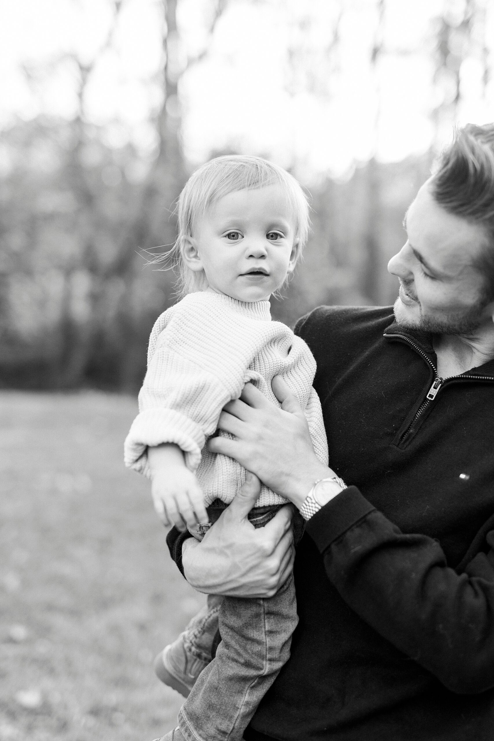dad holds son on hip tickling him during fall family portraits 
