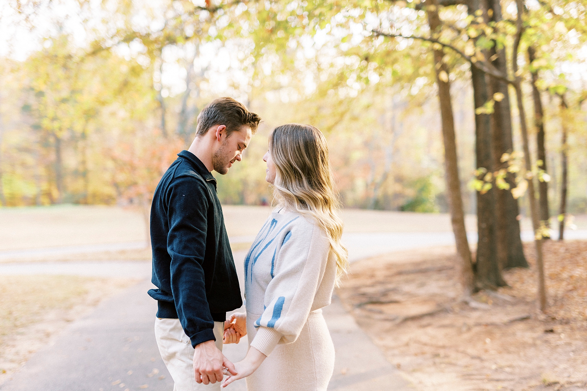 couple holds hands looking at each other during Baker's Creek Park engagement session