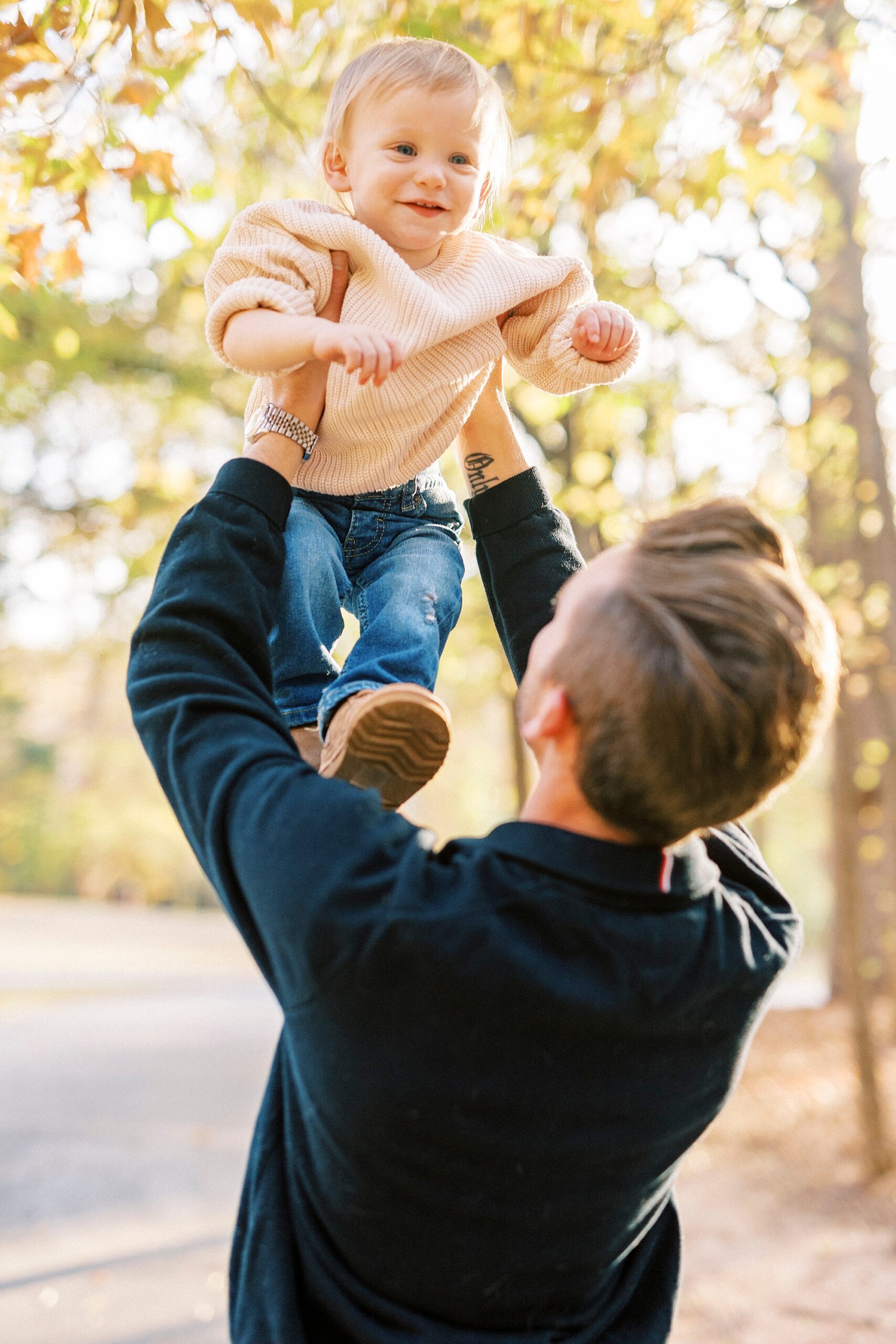 dad lifts up son during fall family photos at Baker's Creek Park