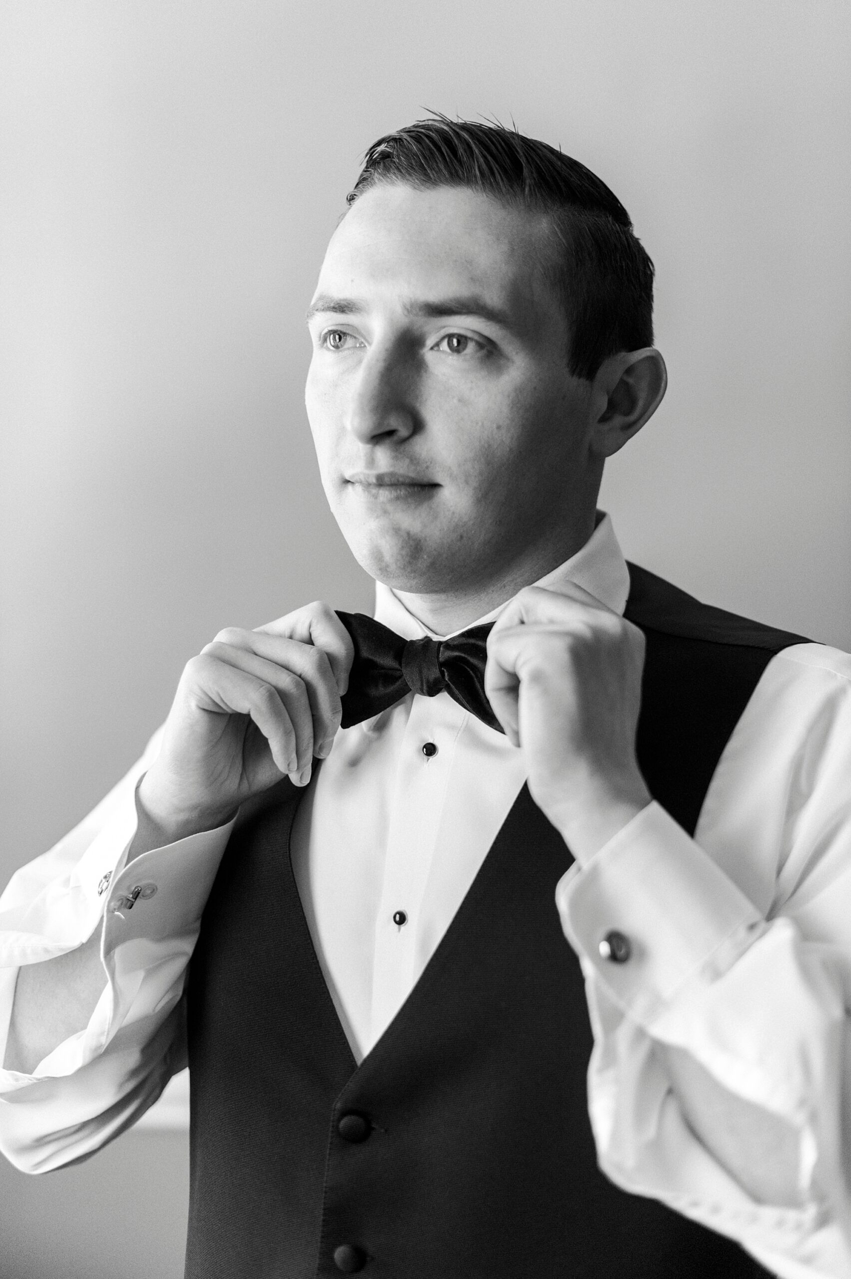 black and white photo of groom adjusting bowtie at Separk Mansion