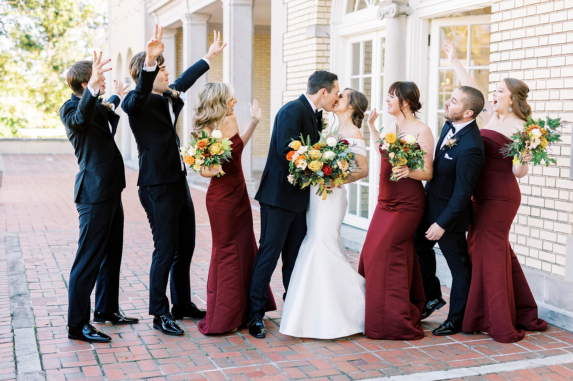 bride and groom kiss while wedding party cheer during fall celebration at Separk Mansion