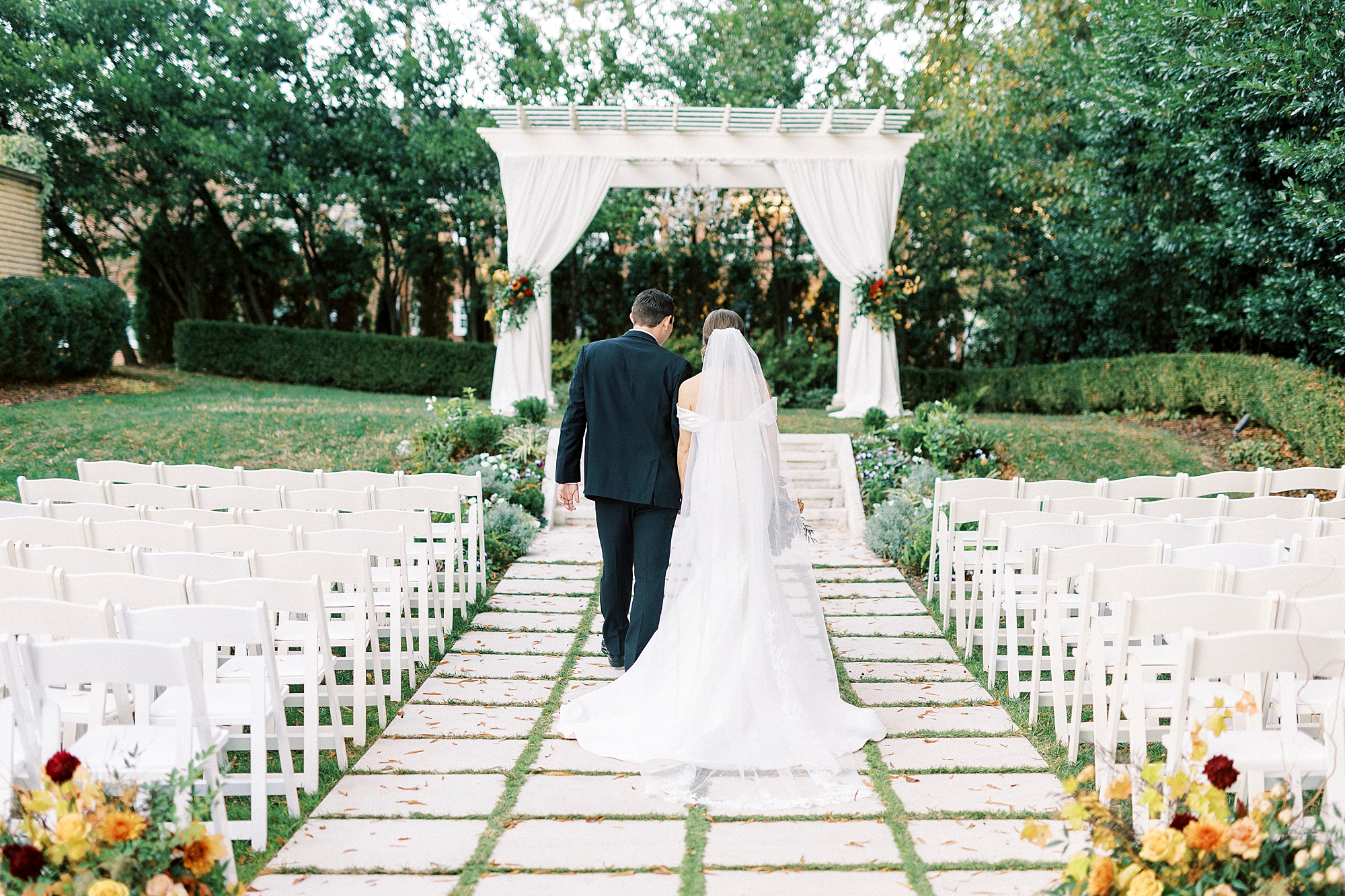 bride and groom walk up aisle in front of gazebo at Separk Mansion