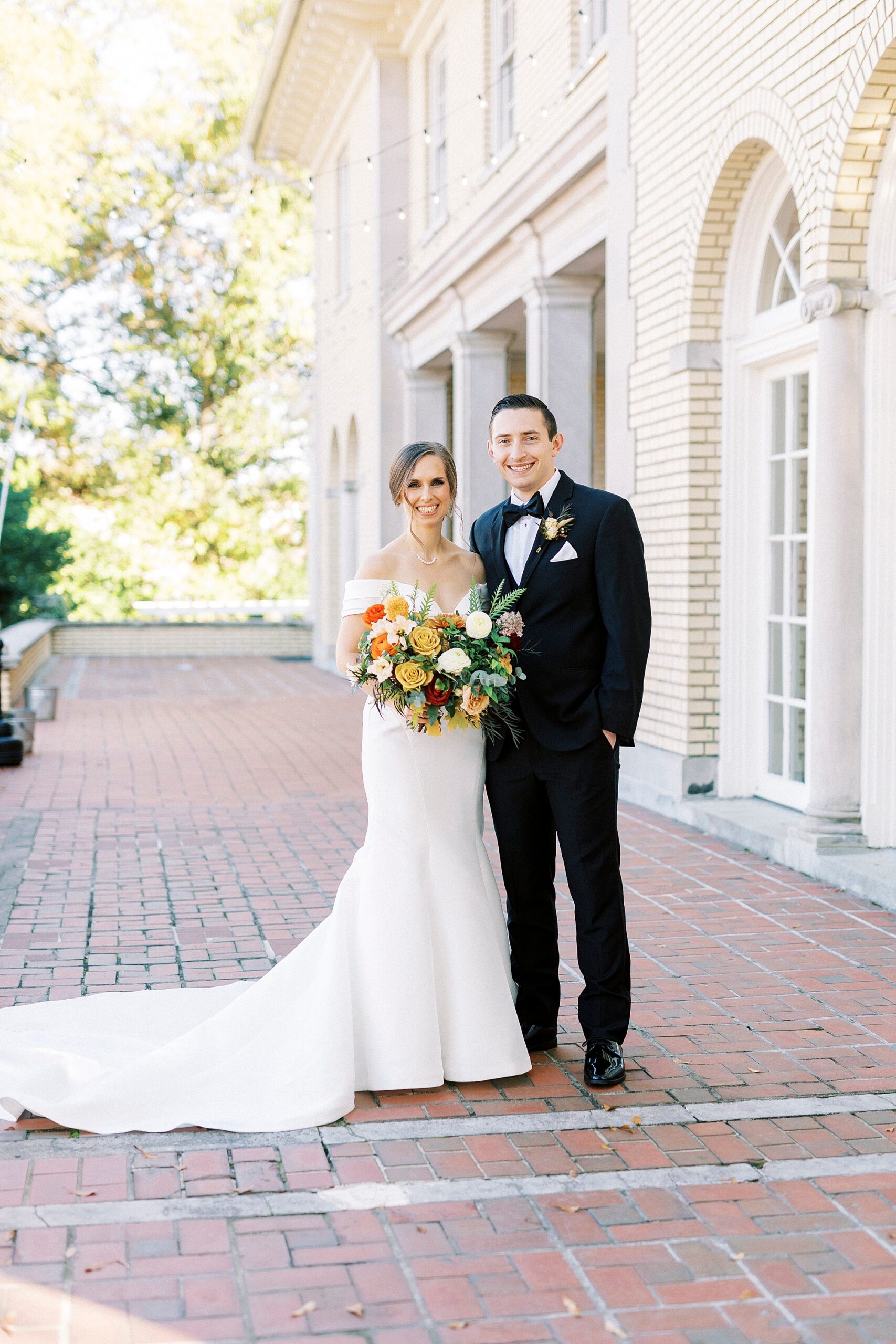 newlyweds stand together on patio during fall wedding photos at Separk Mansion