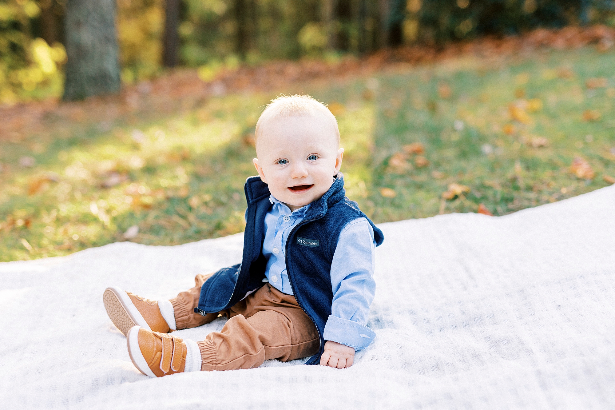 baby sits in blue shirt and vest during fall family photos in Charlotte NC