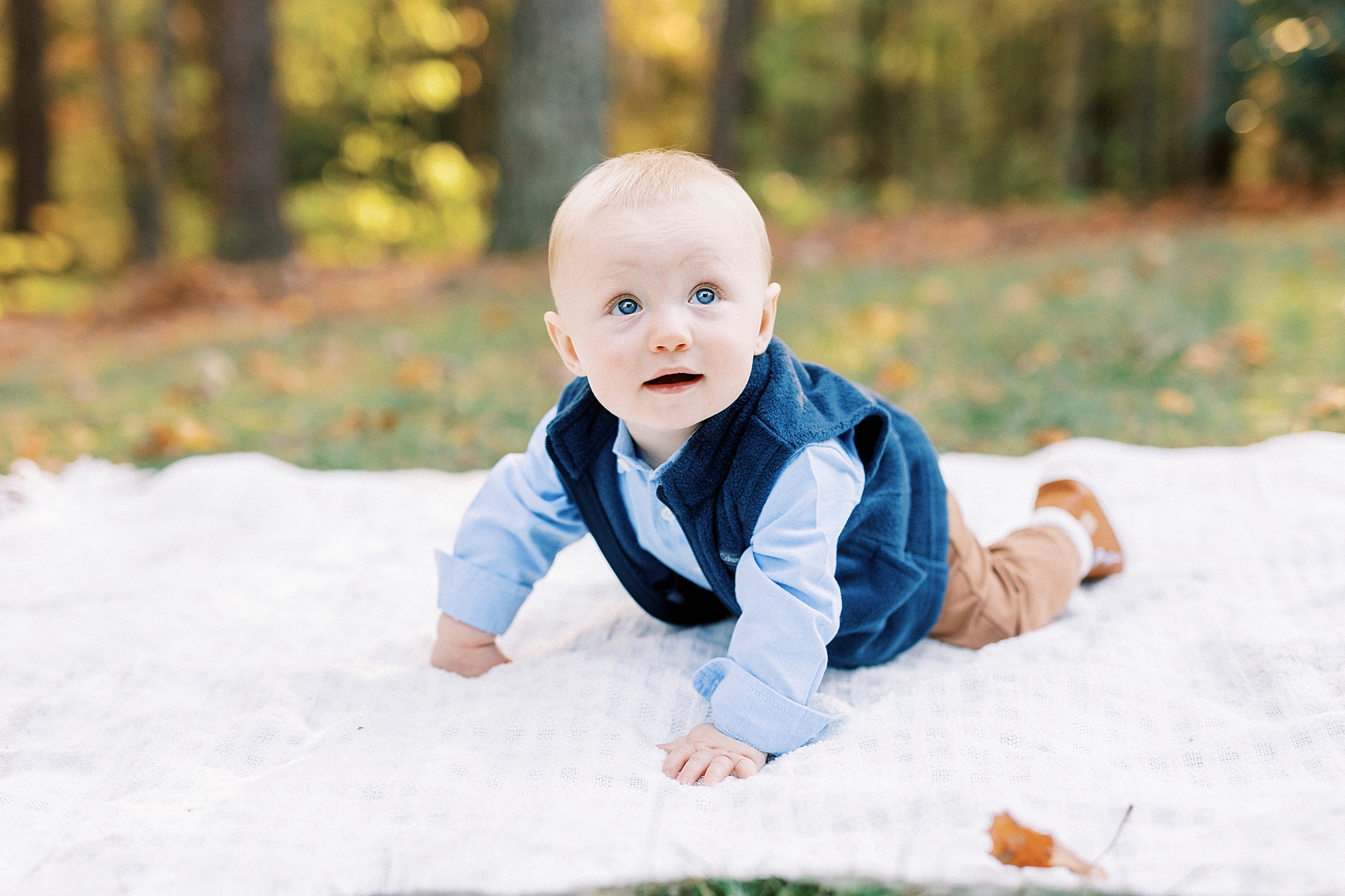 baby boy crawls on blanket during fall family portraits at Charlotte home