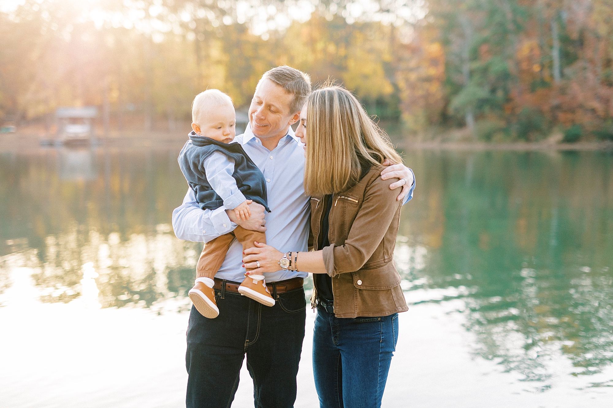parents smile at son on dad's hip during fall family portraits 