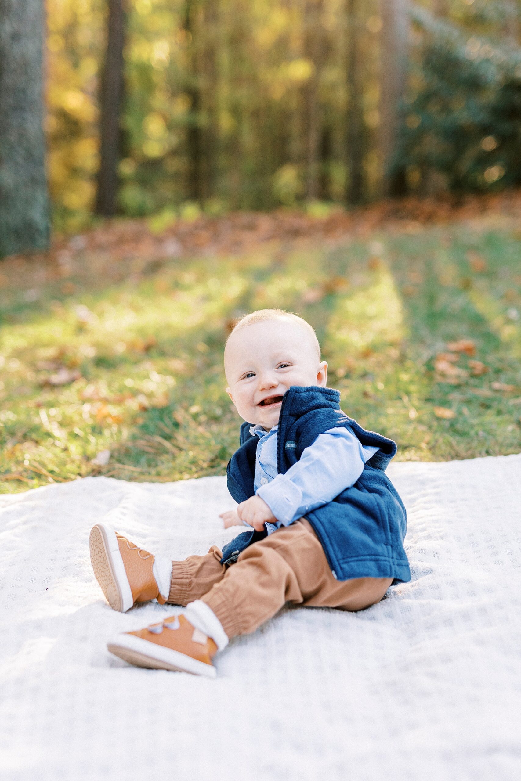 baby laughs falling backwards on blanket during fall family portraits at Charlotte home
