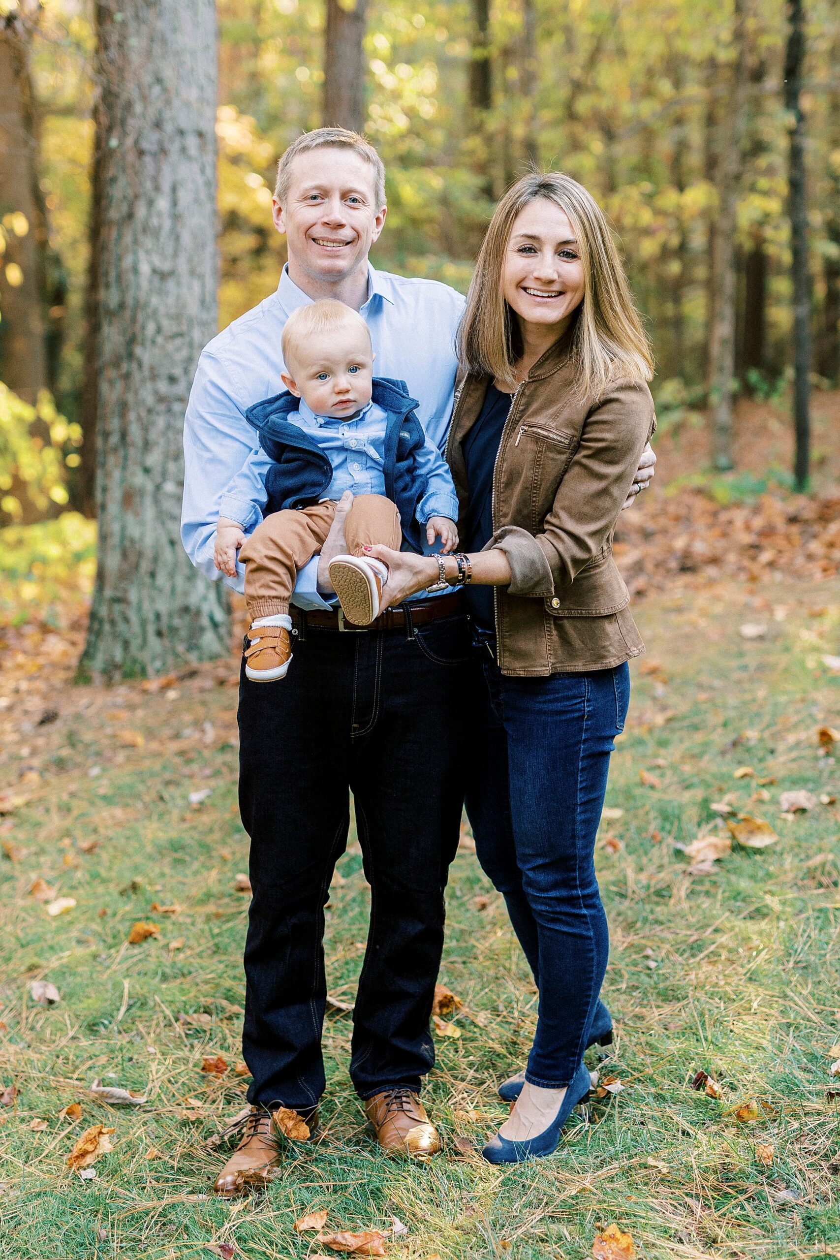 parents smile with son in front of them during fall family portraits at Charlotte home