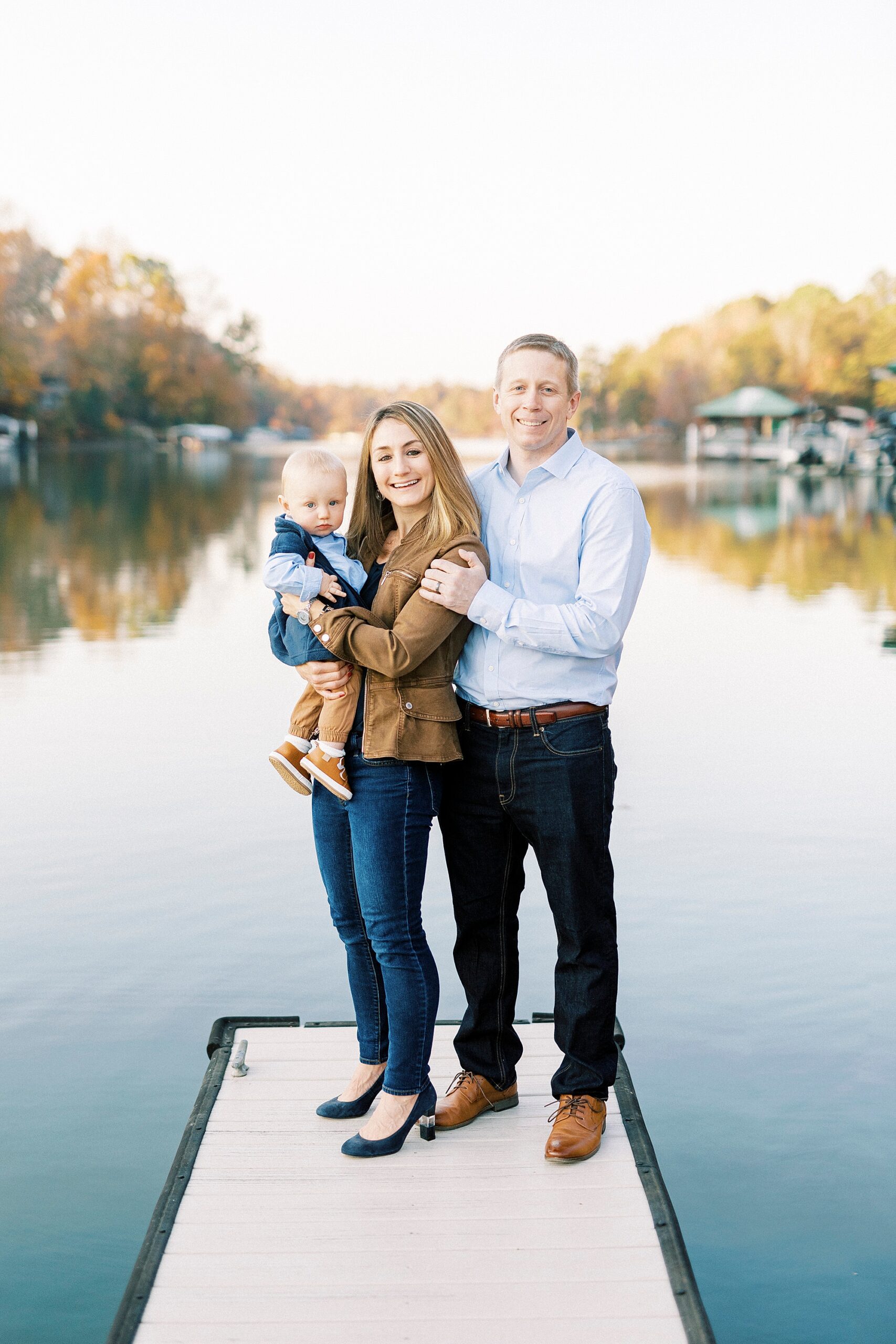 parents pose with son on end of dock outside Charlotte NC home