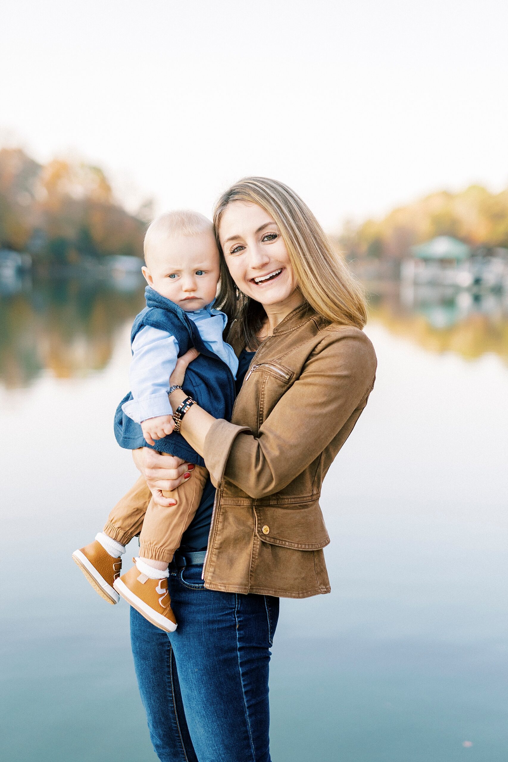 mom smiles leaning into son during fall family portraits at Charlotte home