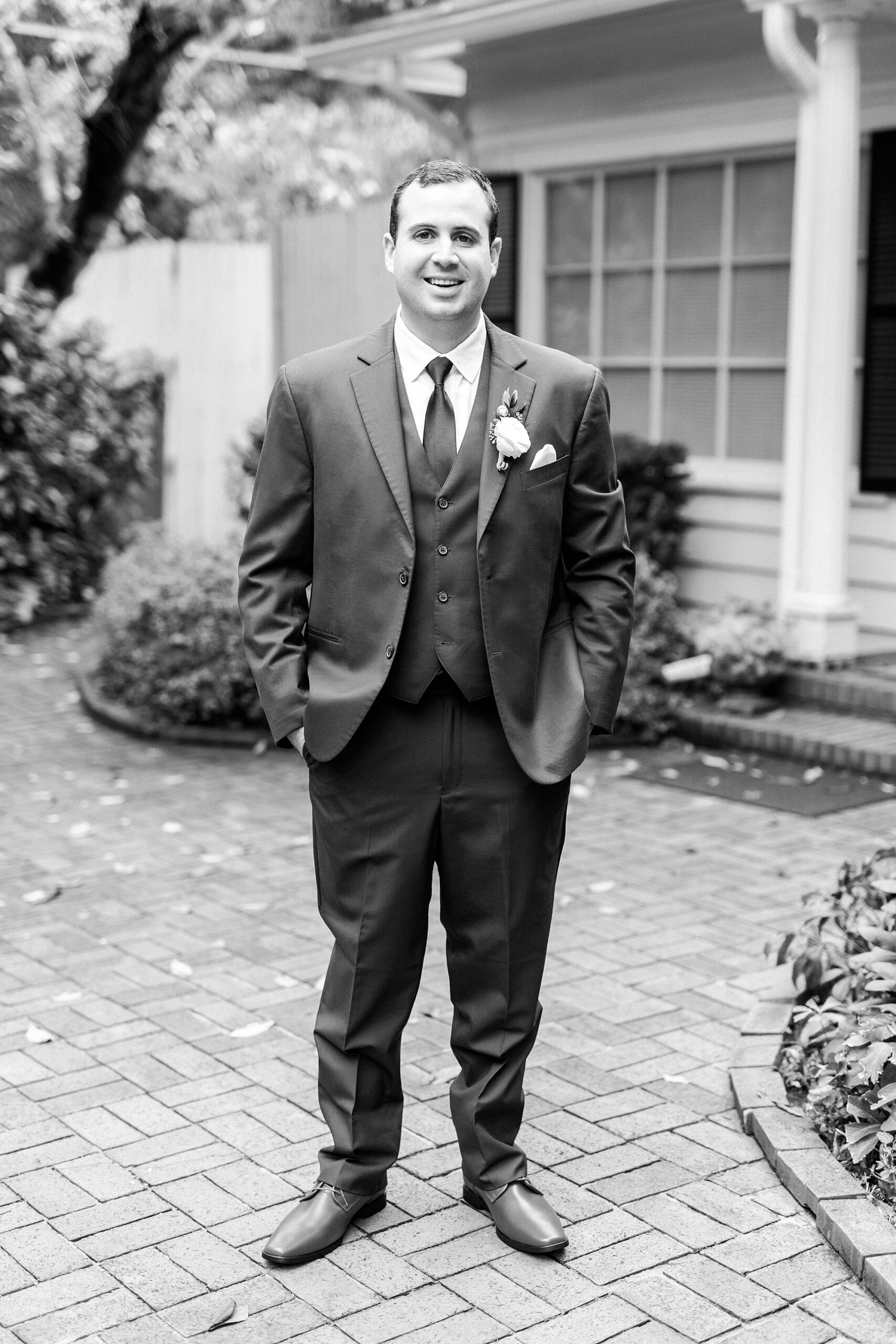 groom stands with hands in pocket outside the Morehead Inn on patio
