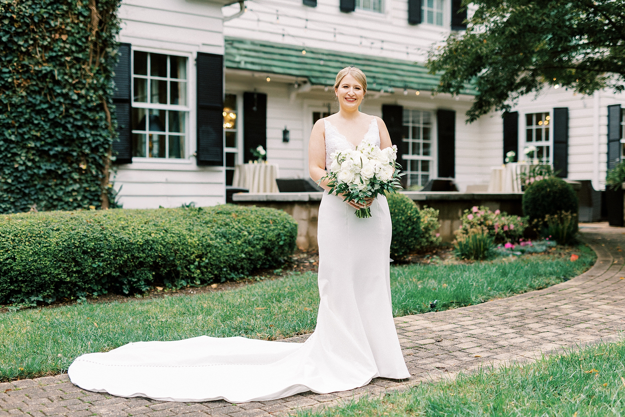bride holds bouquet of ivory flowers before fall wedding at the Morehead Inn