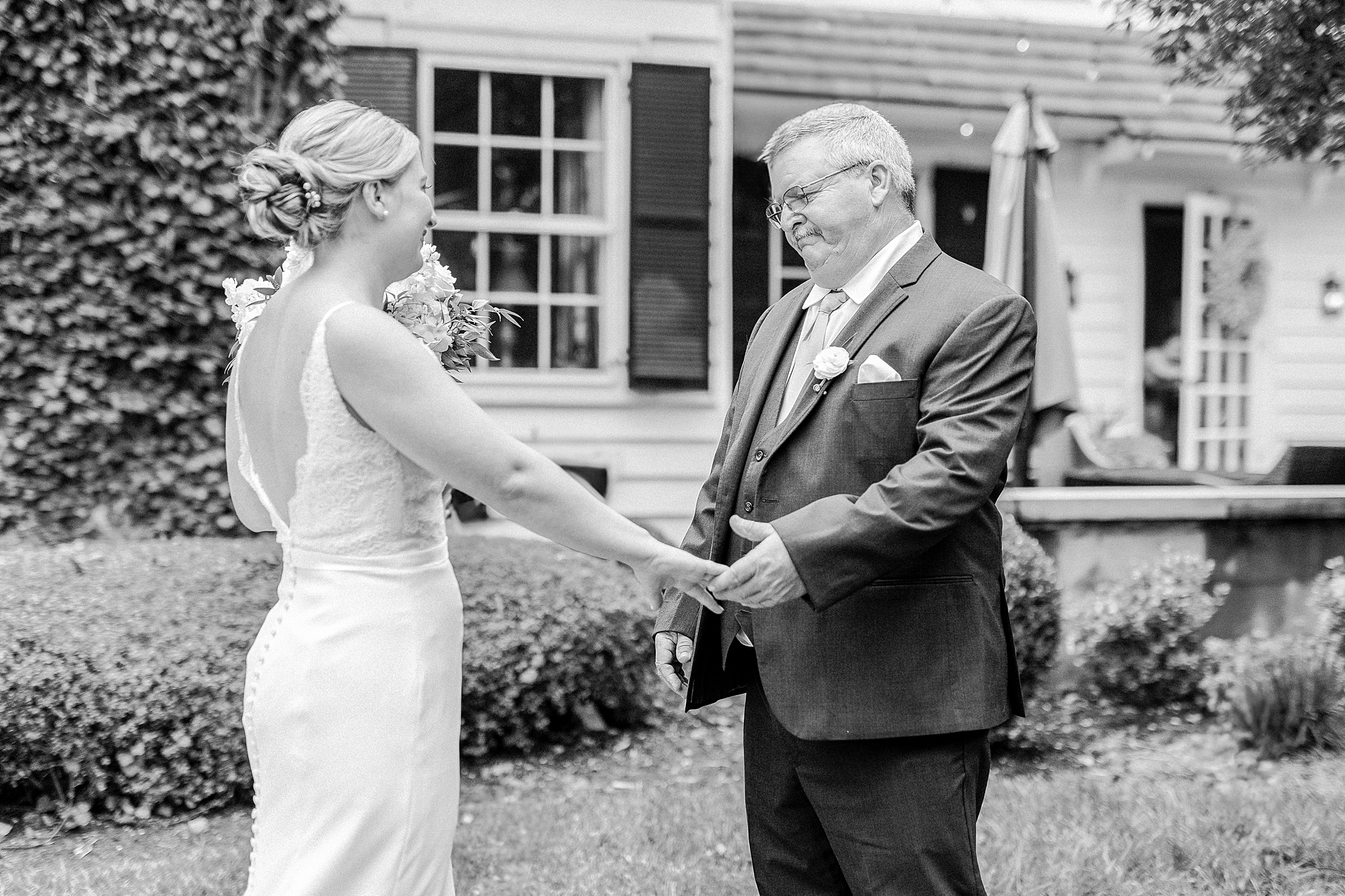 bride and father hold hands outside the Morehead Inn during first look