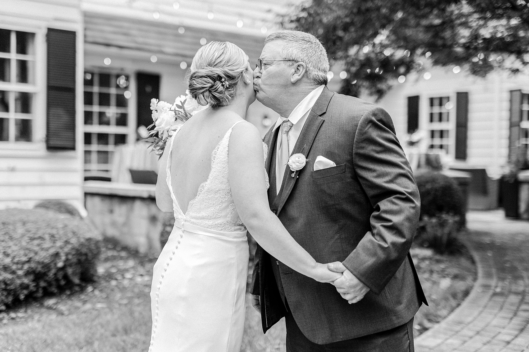 father leans to kiss bride's cheek during first look outside the Morehead Inn
