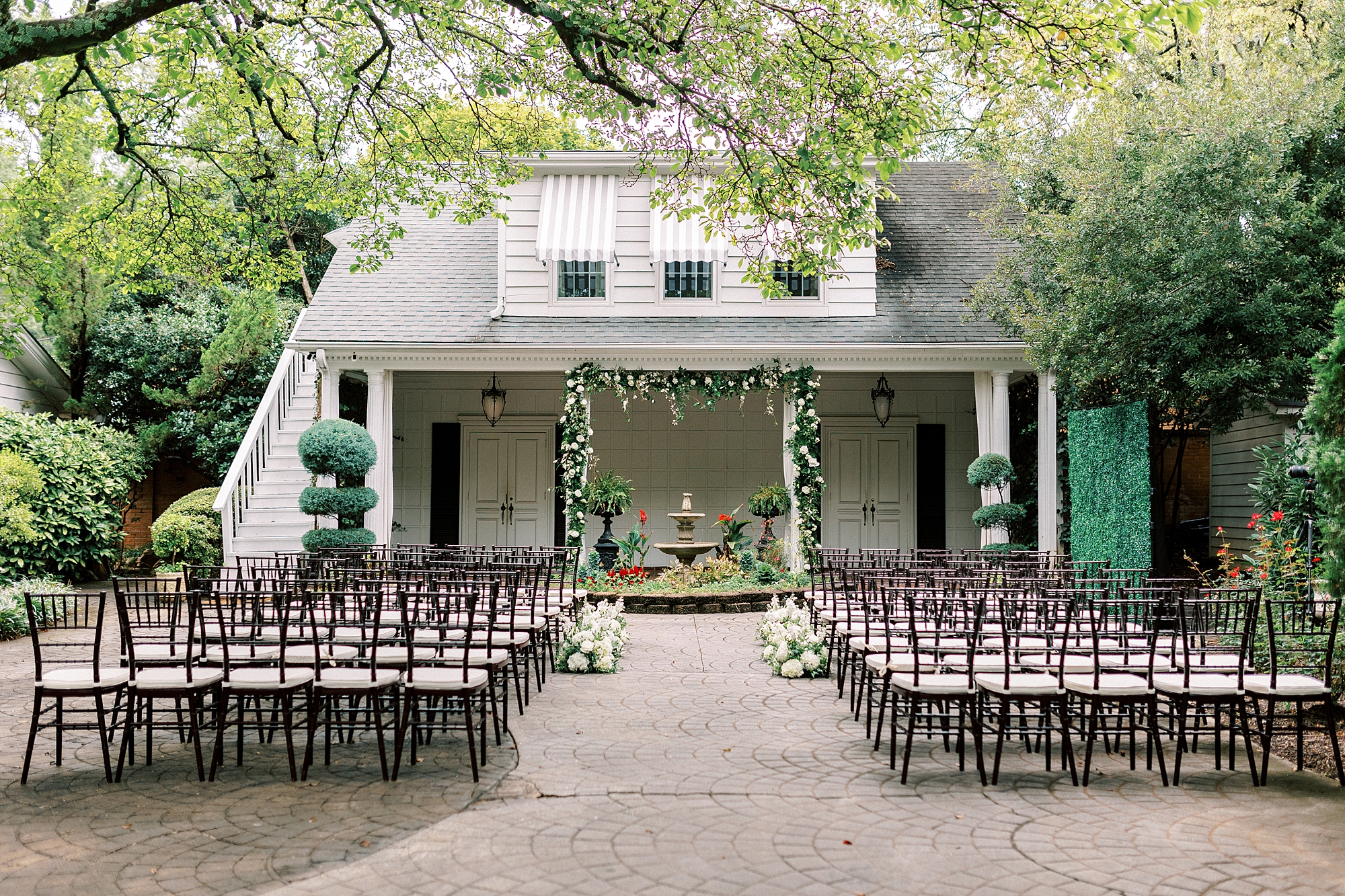 ceremony site on patio at the Morehead Inn with arbor of white flowers 