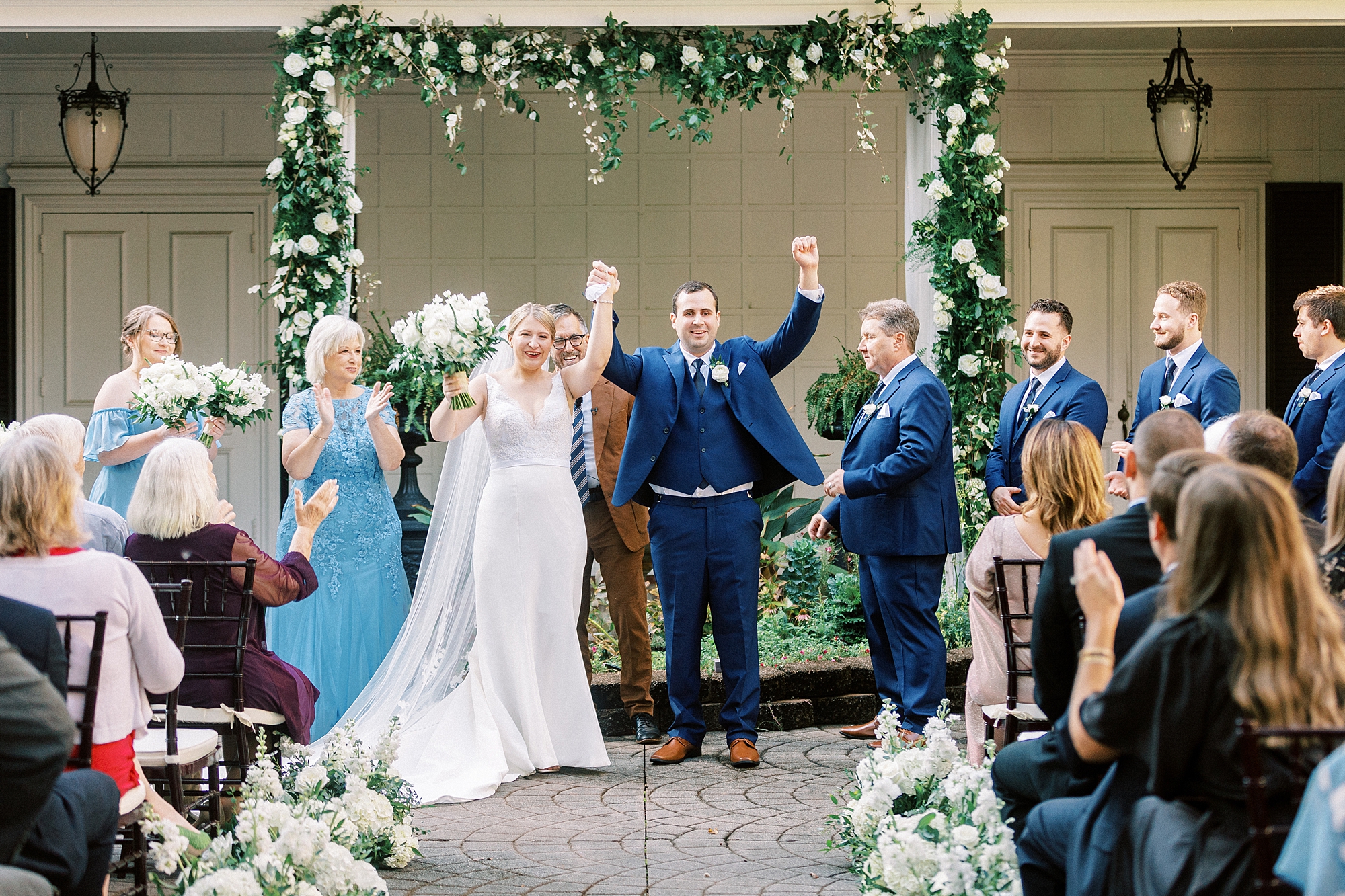 bride and groom cheer under arbor on patio at the Morehead Inn