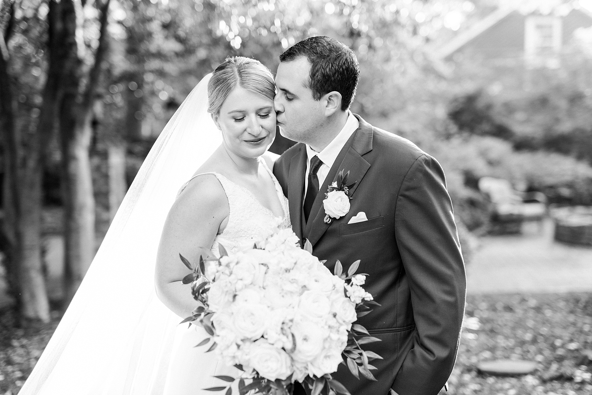groom kisses bride's cheek during portraits at the Morehead Inn