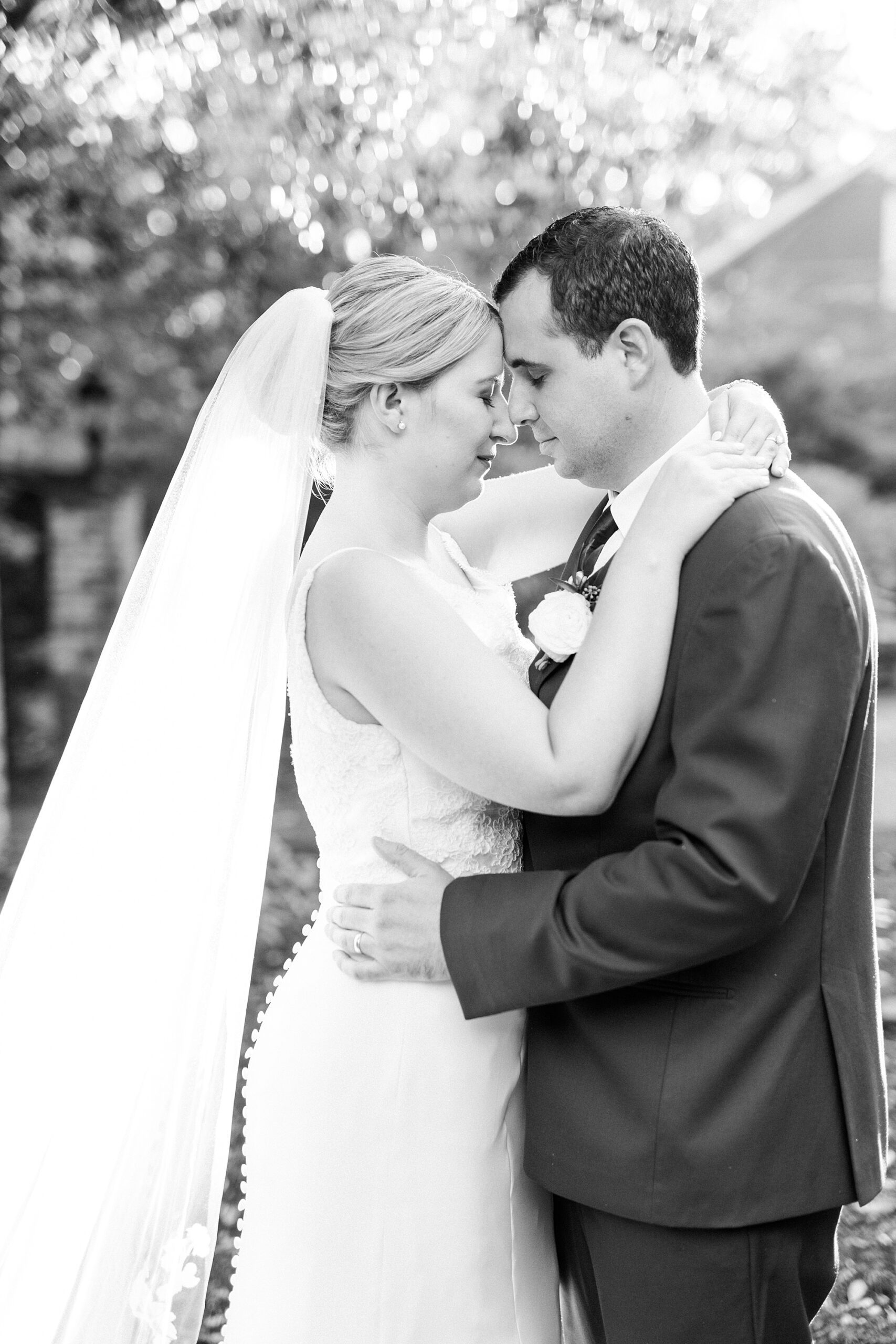bride and groom hug with veil draped behind them