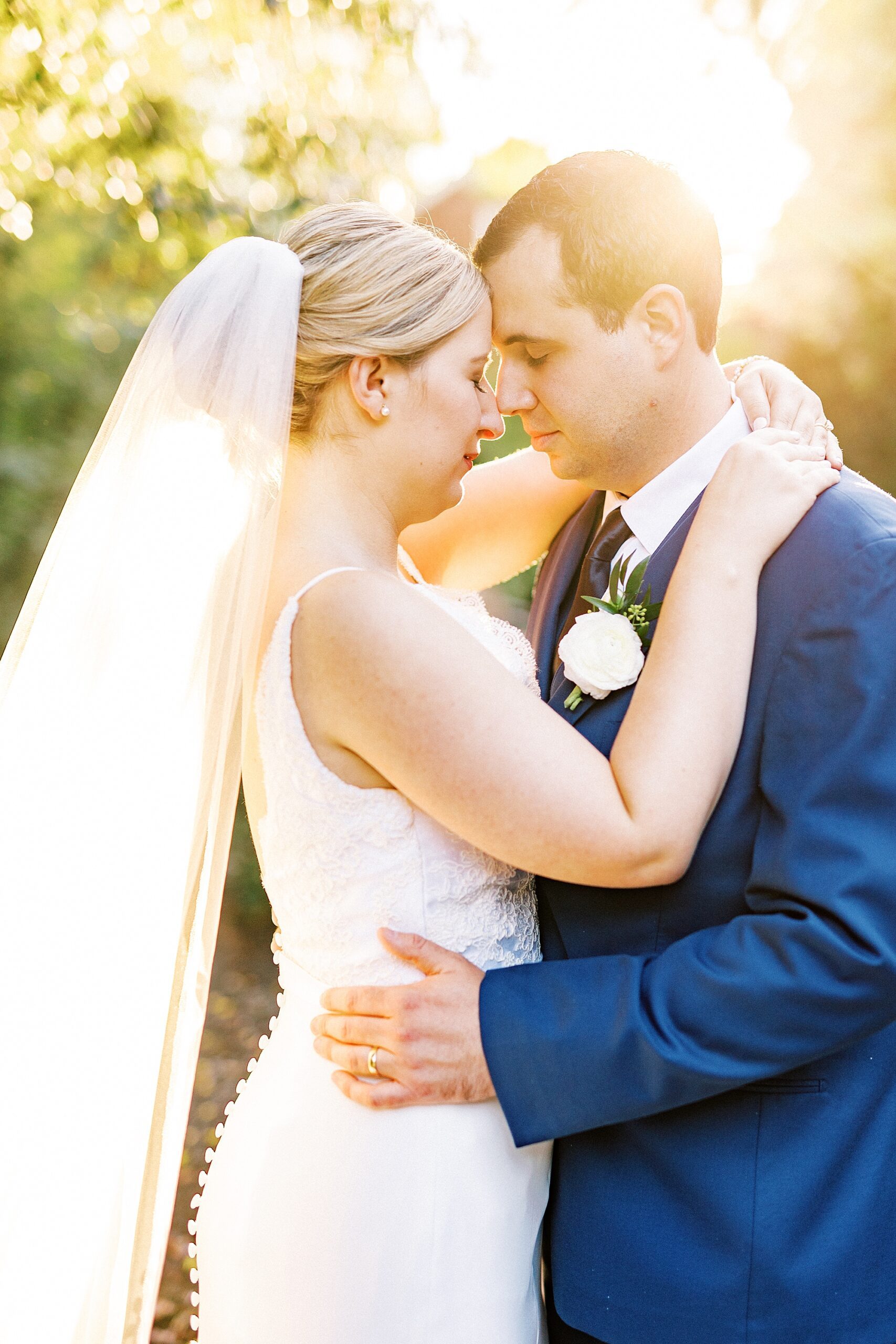 bride and groom hug with flare of sun during NC wedding day