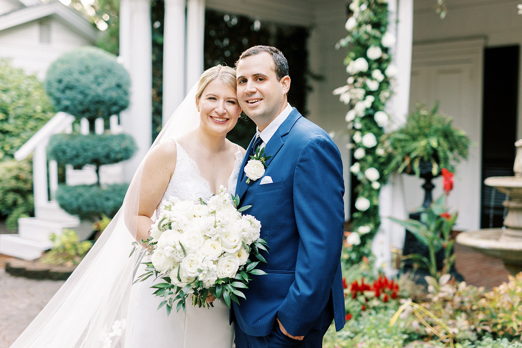 newlyweds lean together by front porch of the Morehead Inn