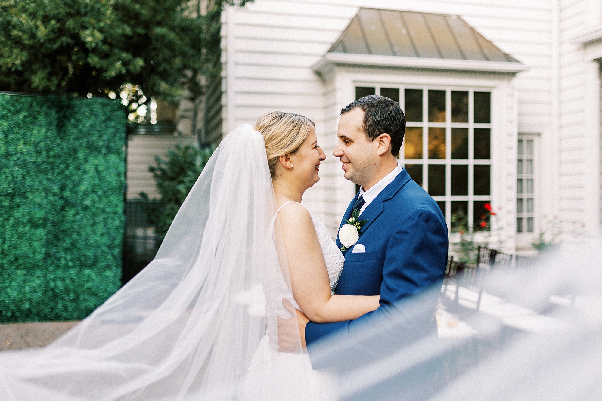 newlyweds lean nuzzling noses with veil around them at the Morehead Inn