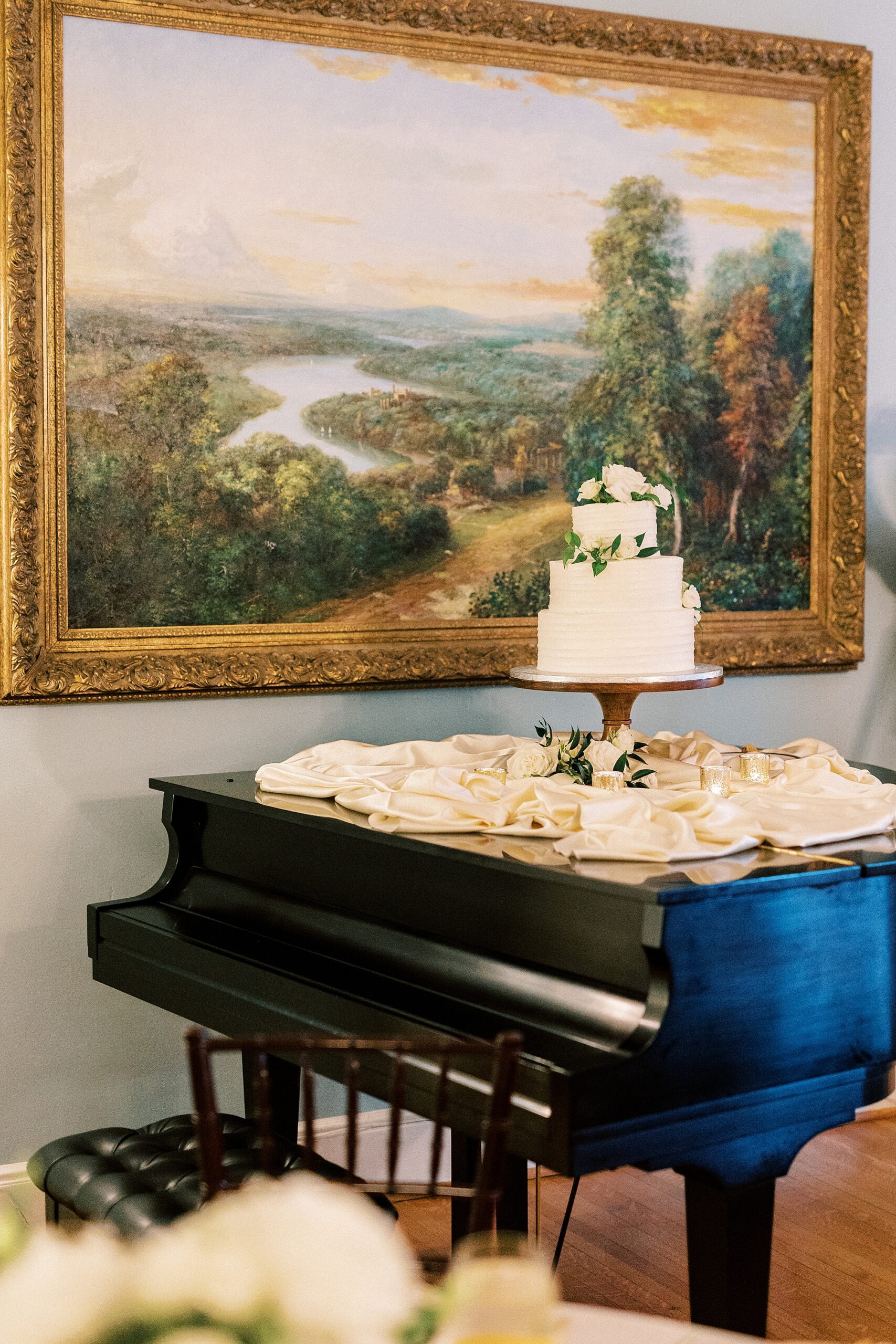 tiered wedding cake sits on top of piano at the Morehead Inn