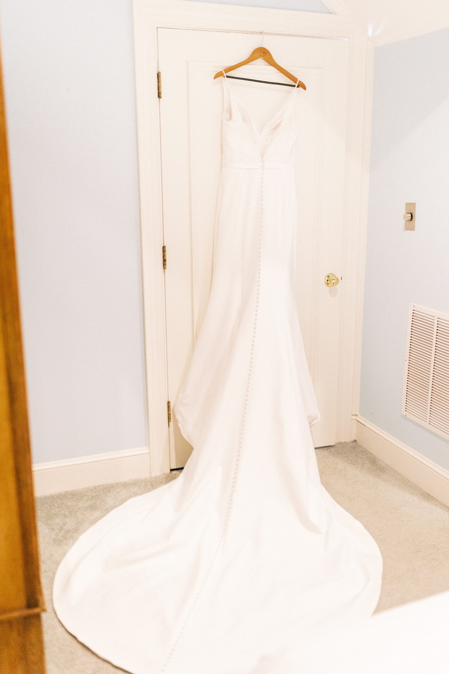wedding dress hangs on door in suite at the Morehead Inn