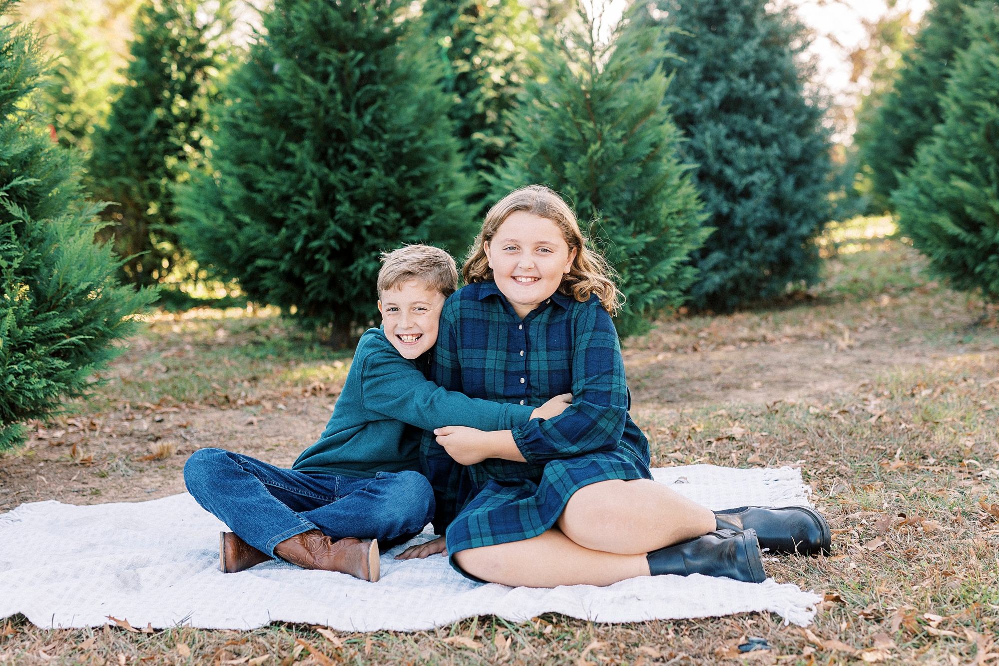 two siblings hug on white blanket during Almond Christmas Tree Farm mini sessions