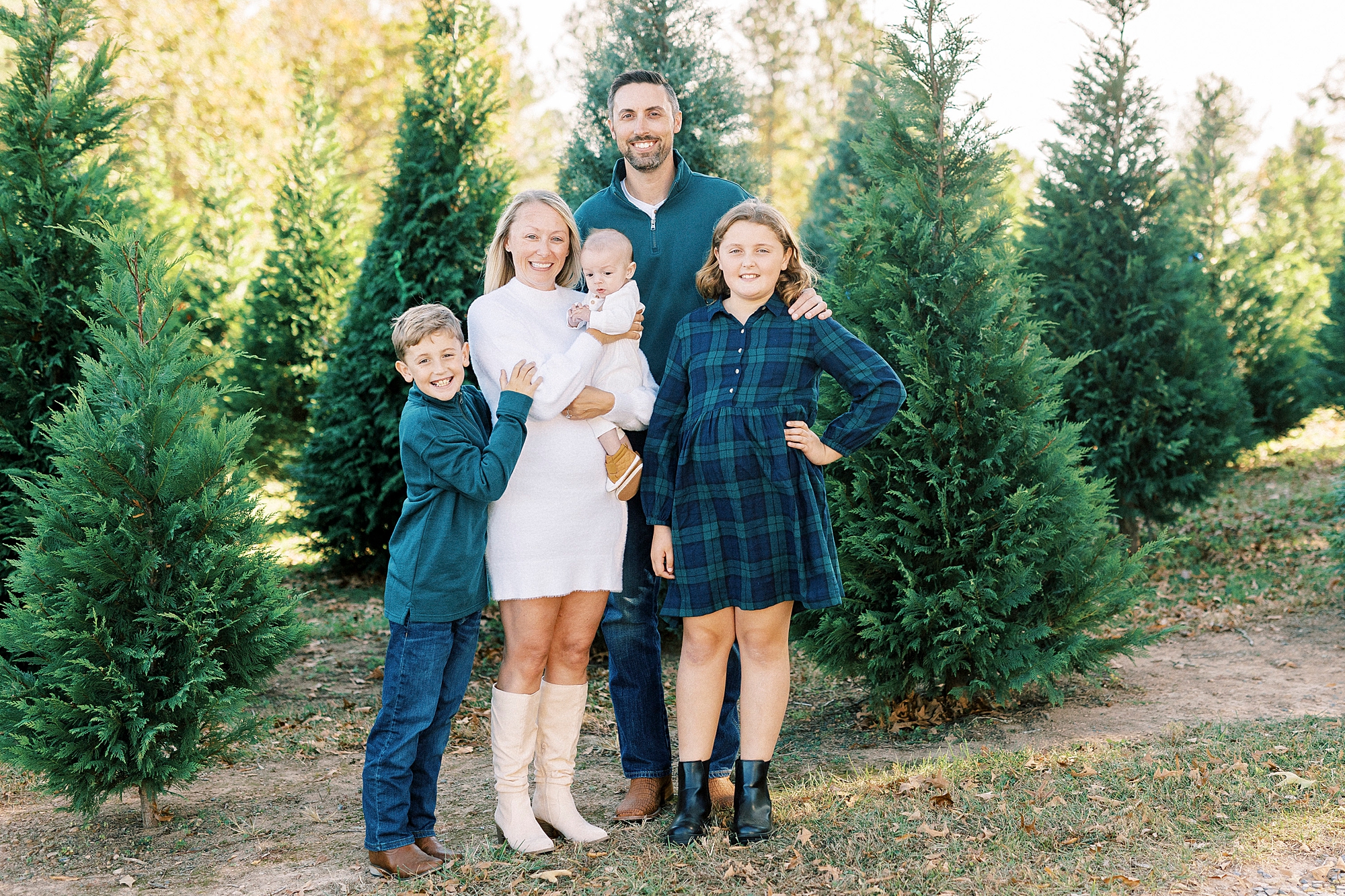 parents hug three children in front of threes at Almond Christmas Tree Farm