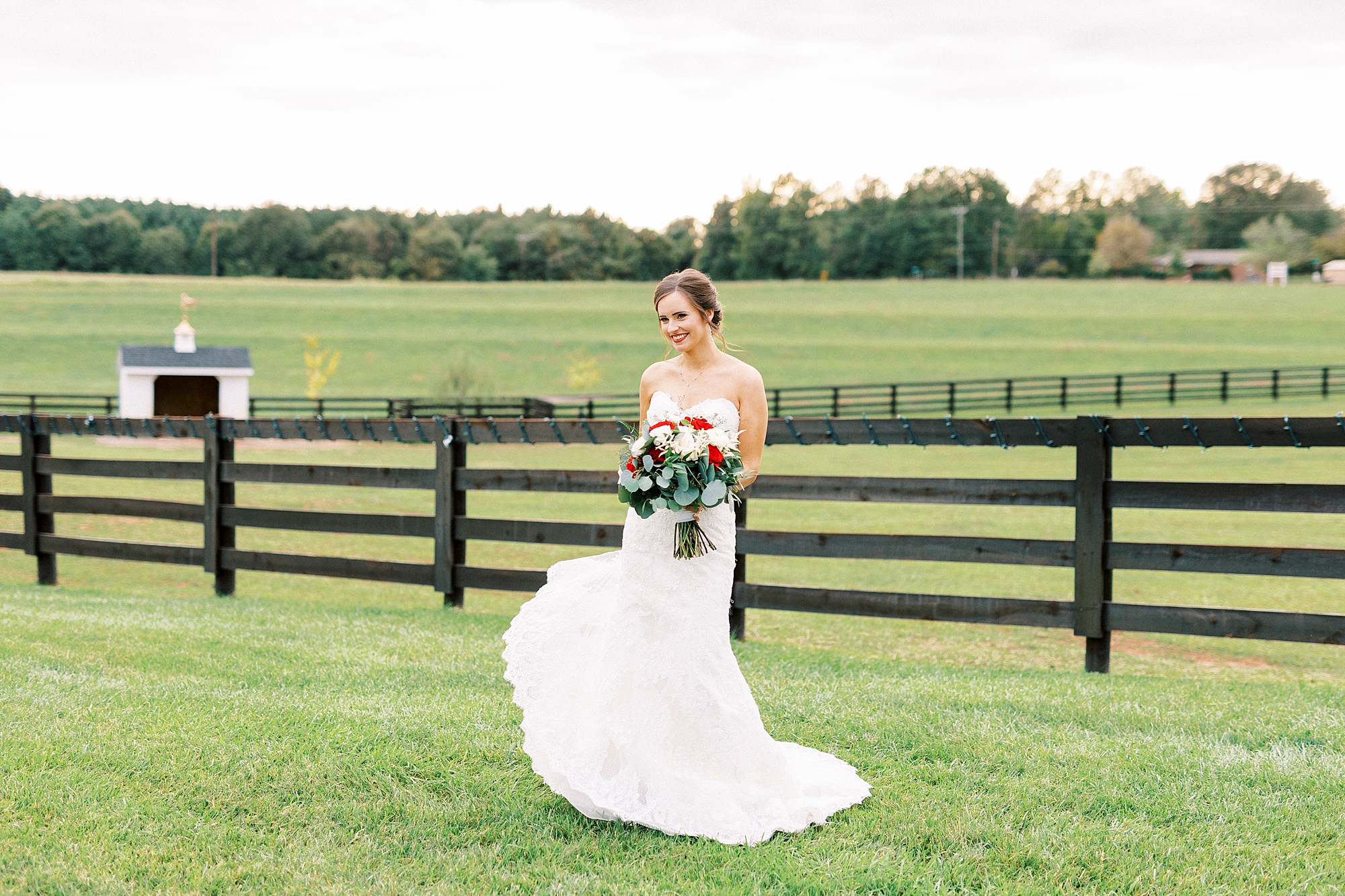 bride twirls in wedding dress in front of fence at Chickadee Hill Farms