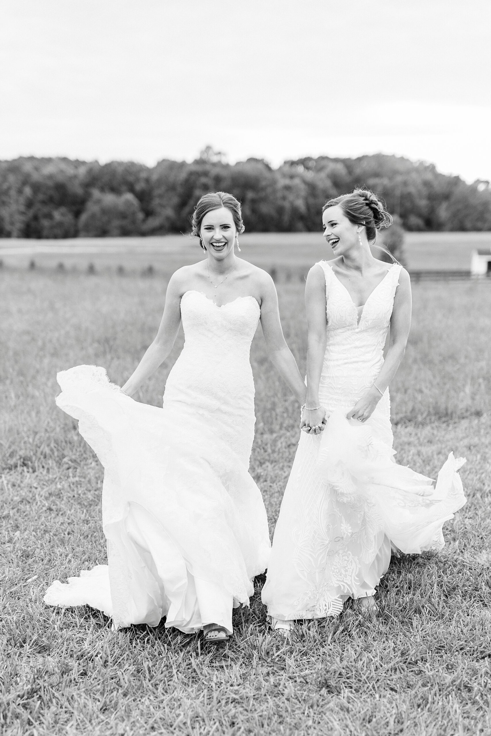 sisters hold hands walking in wedding gowns at Chickadee Hill Farms