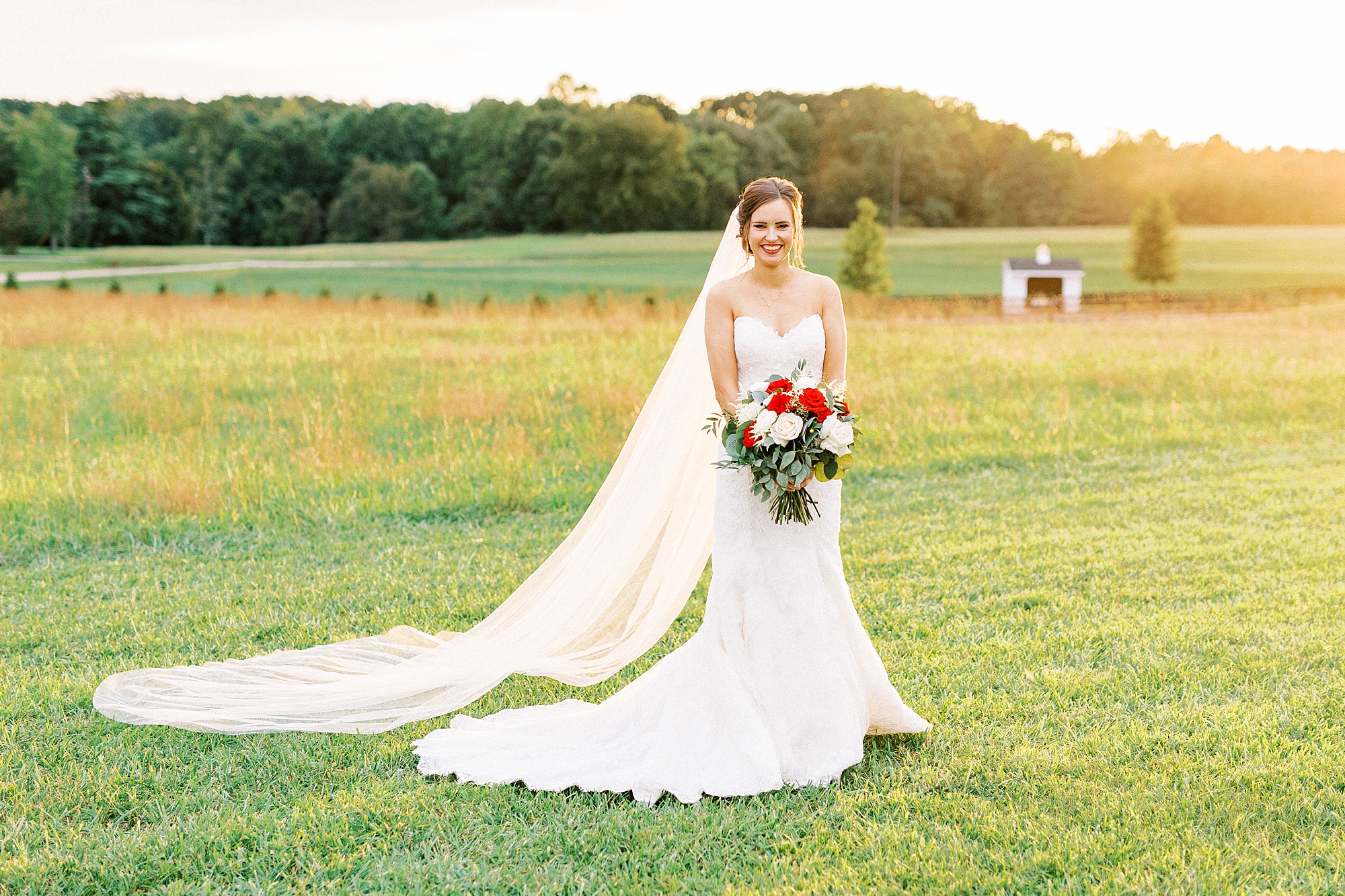 bride holds bouquet of white and red flowers at Chickadee Hill Farms