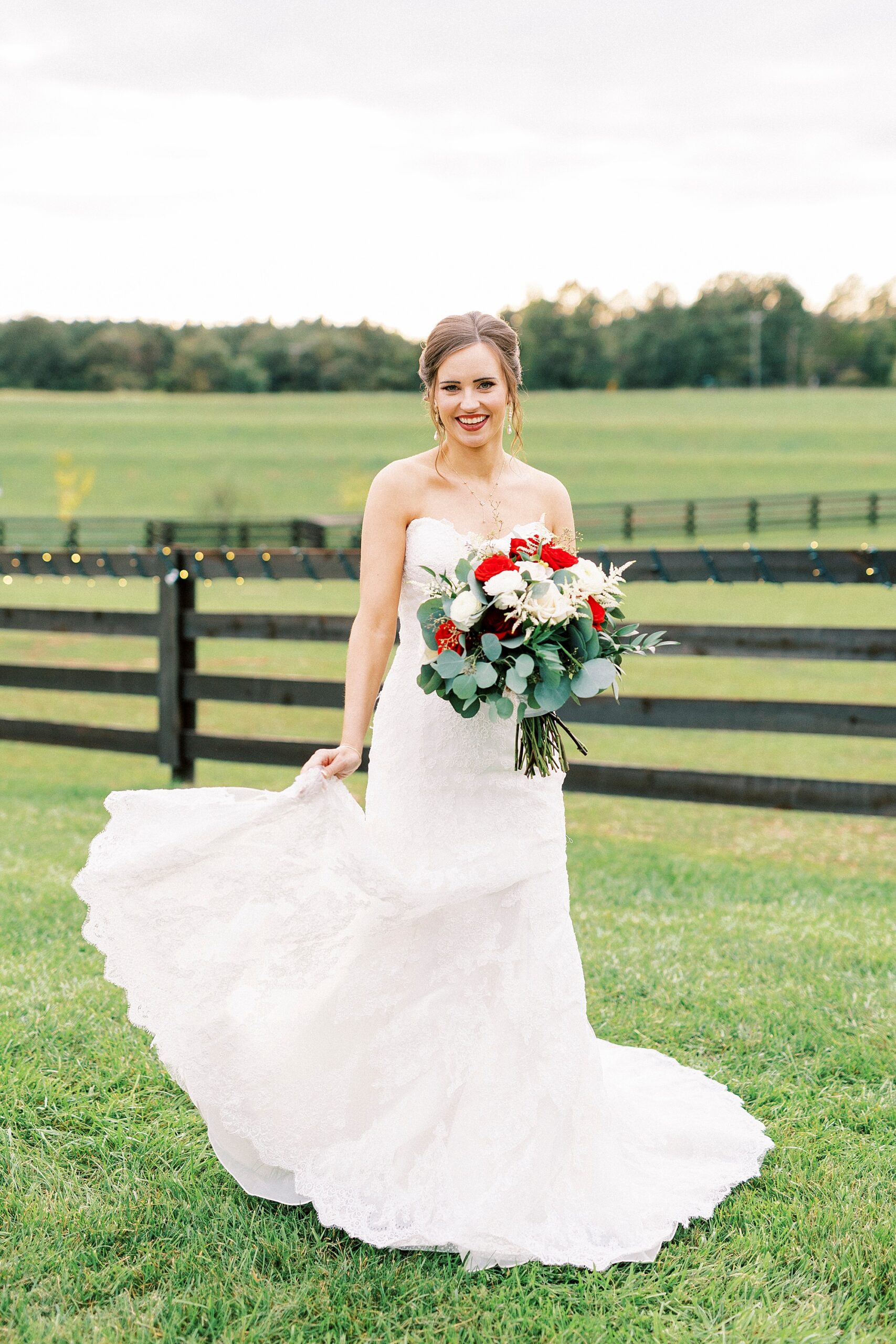 bride twirls in wedding dress holding bouquet of red and white flowers 