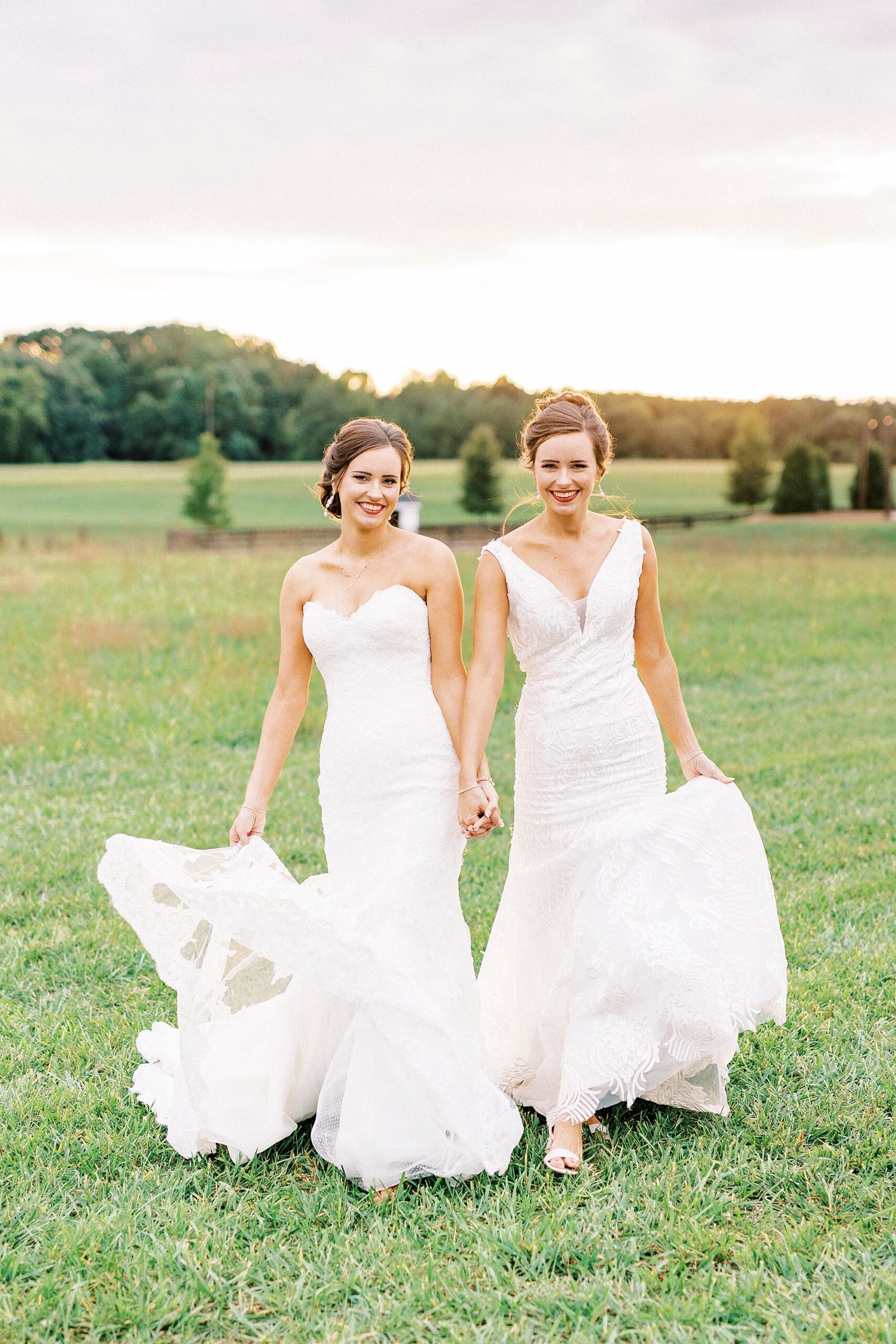 bride and sister hold hands walking together in front of sunset at Chickadee Hill Farms