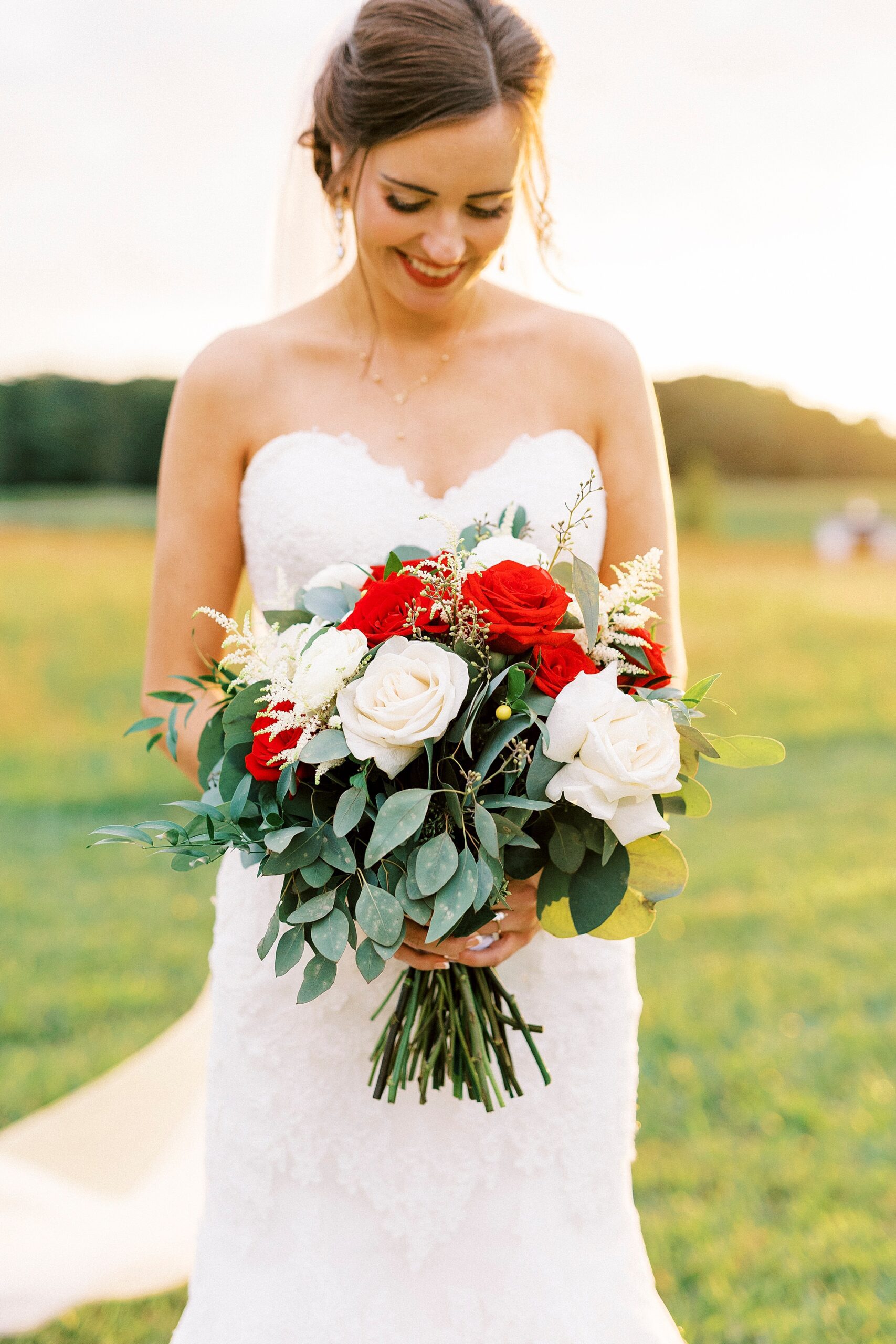 bride in strapless wedding gown holds bouquet of red and white flowers 