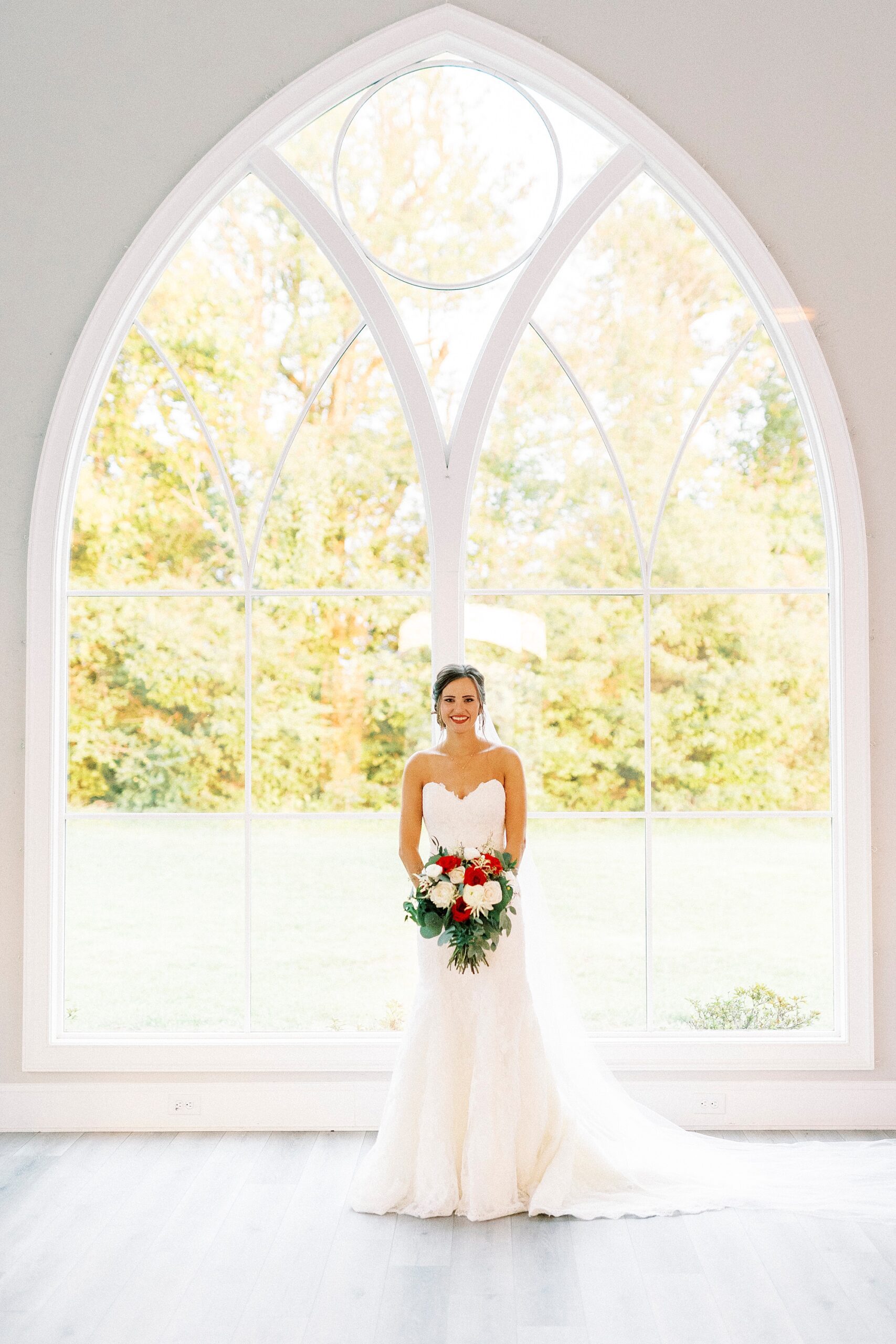 bride poses in front of large window in chapel at Chickadee Hill Farms