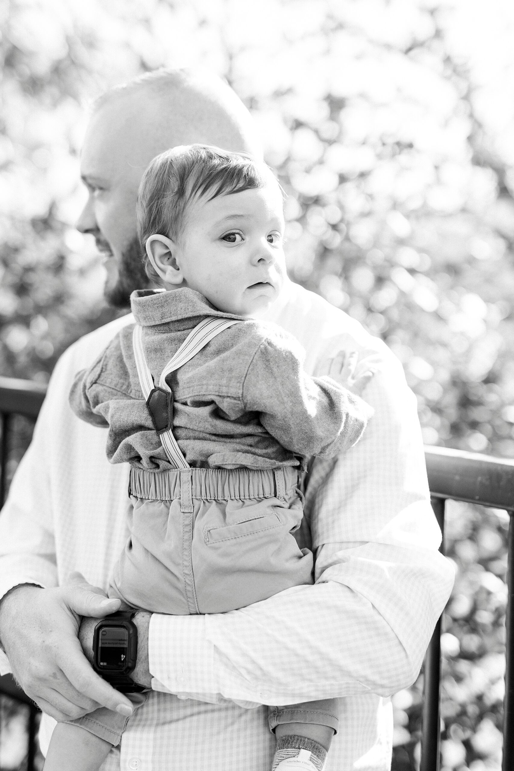 dad holds baby boy in suspenders on bridge in North Carolina 