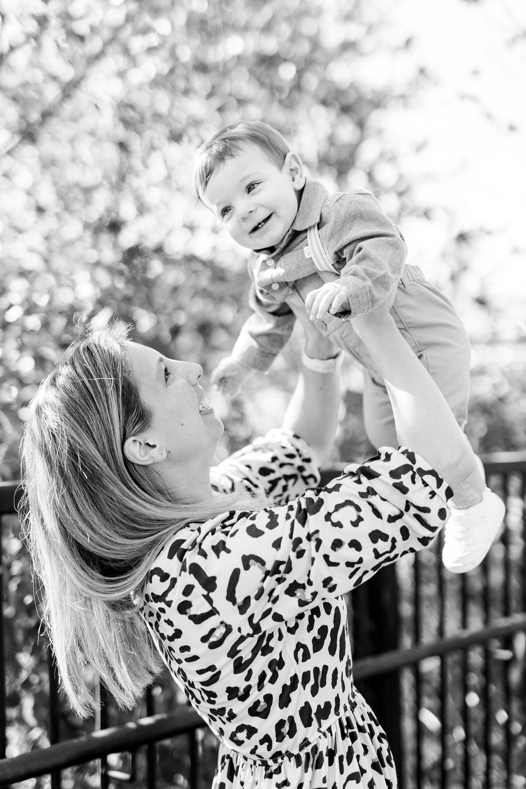 mom lifts up baby boy during lifestyle fall family portraits on bridge 