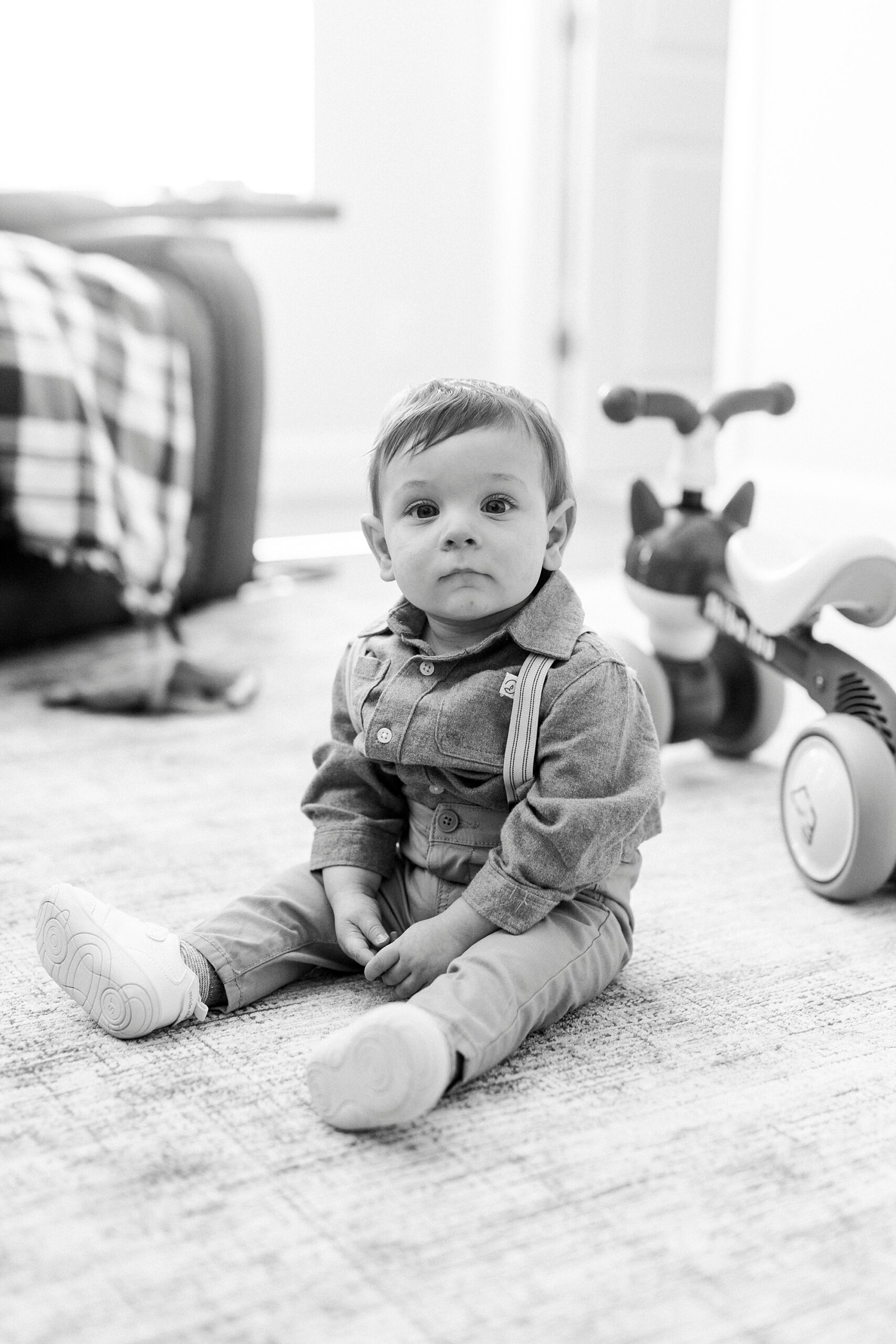 toddler baby sits on floor in front of bike during fall photos 