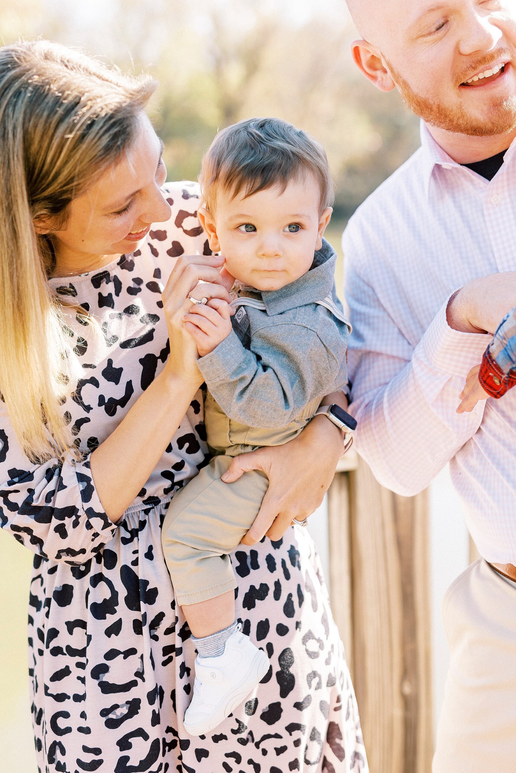 parents hold sons and mom leans to talk to baby boy during fall family photos in Cramerton NC