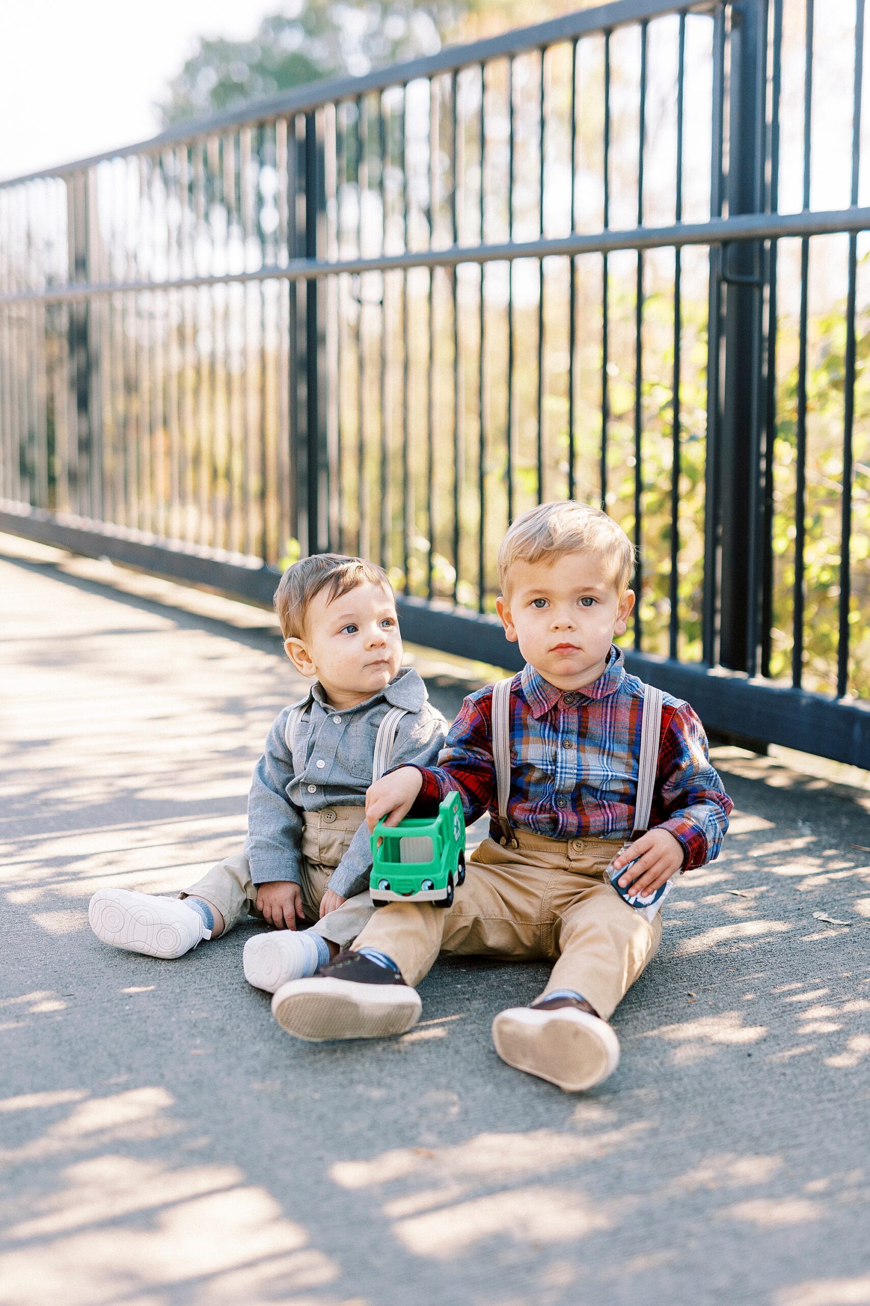 brothers sit together on bridge during fall family photos in Cramerton NC