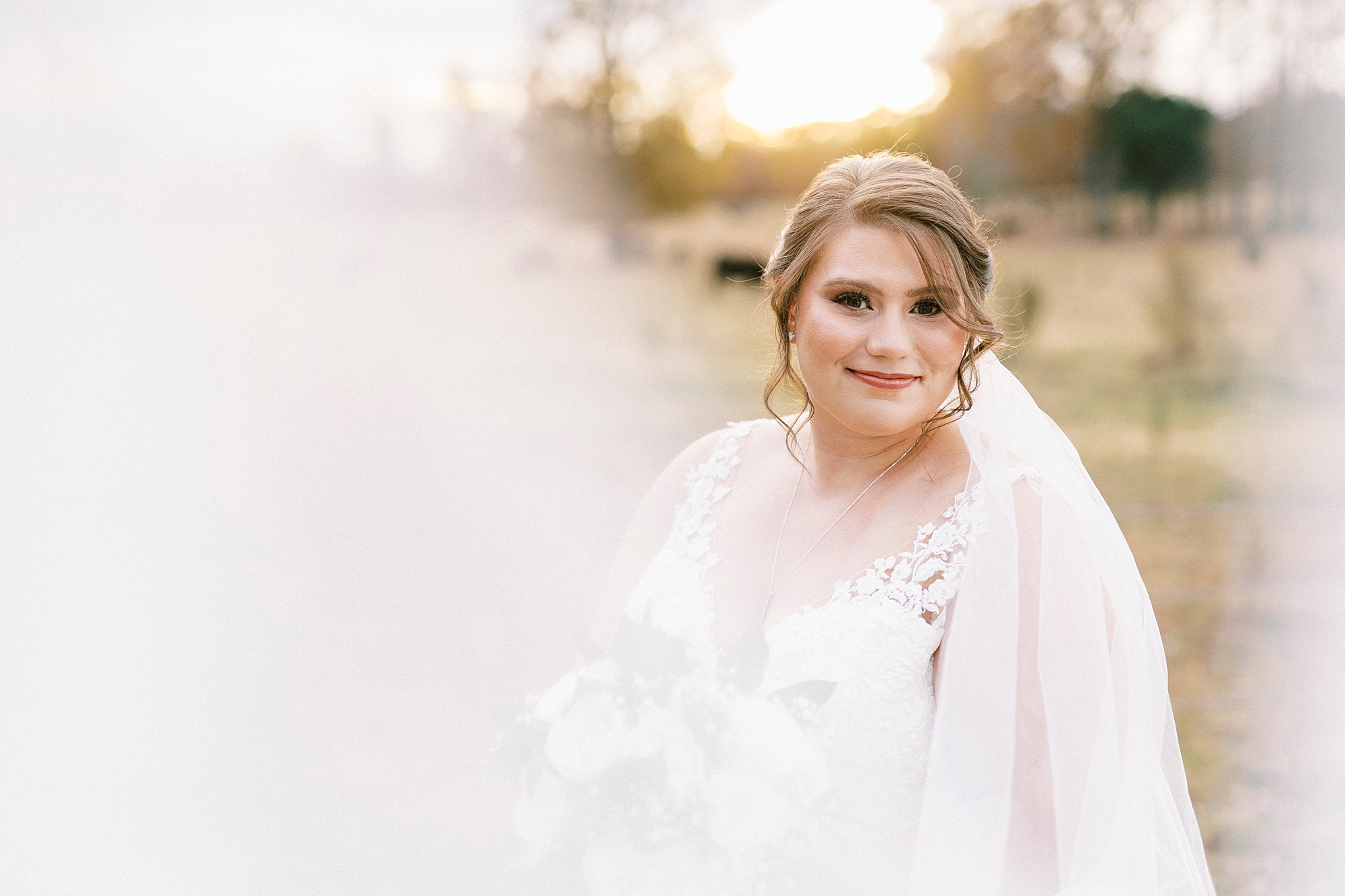 bride smiles in wedding dress with veil around her during bridal portraits at the Farm at Brusharbor