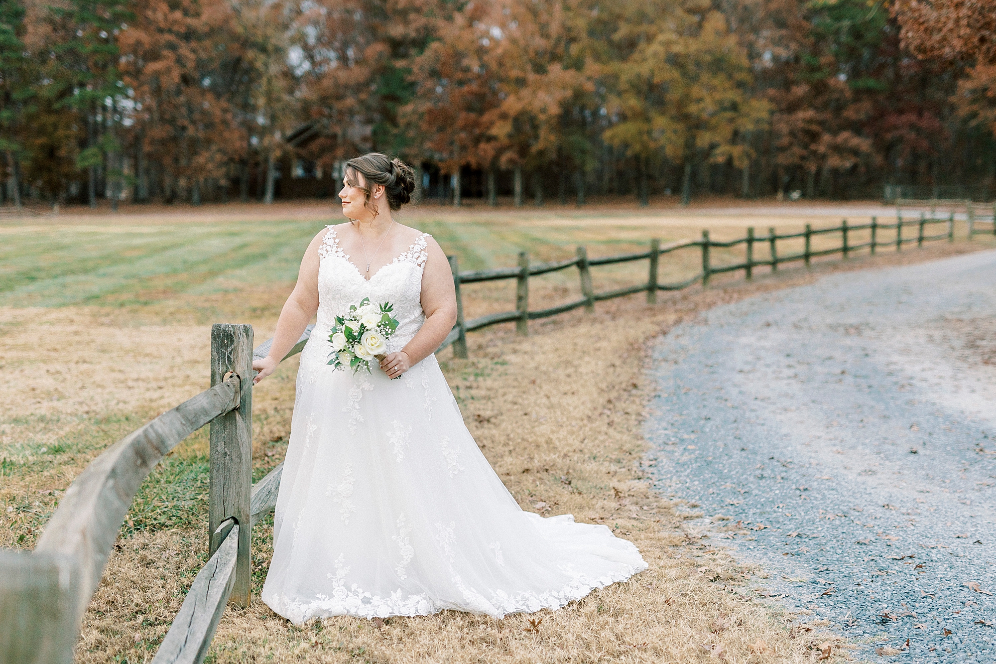 bride stands by wooden fence at the Farm at Brusharbor