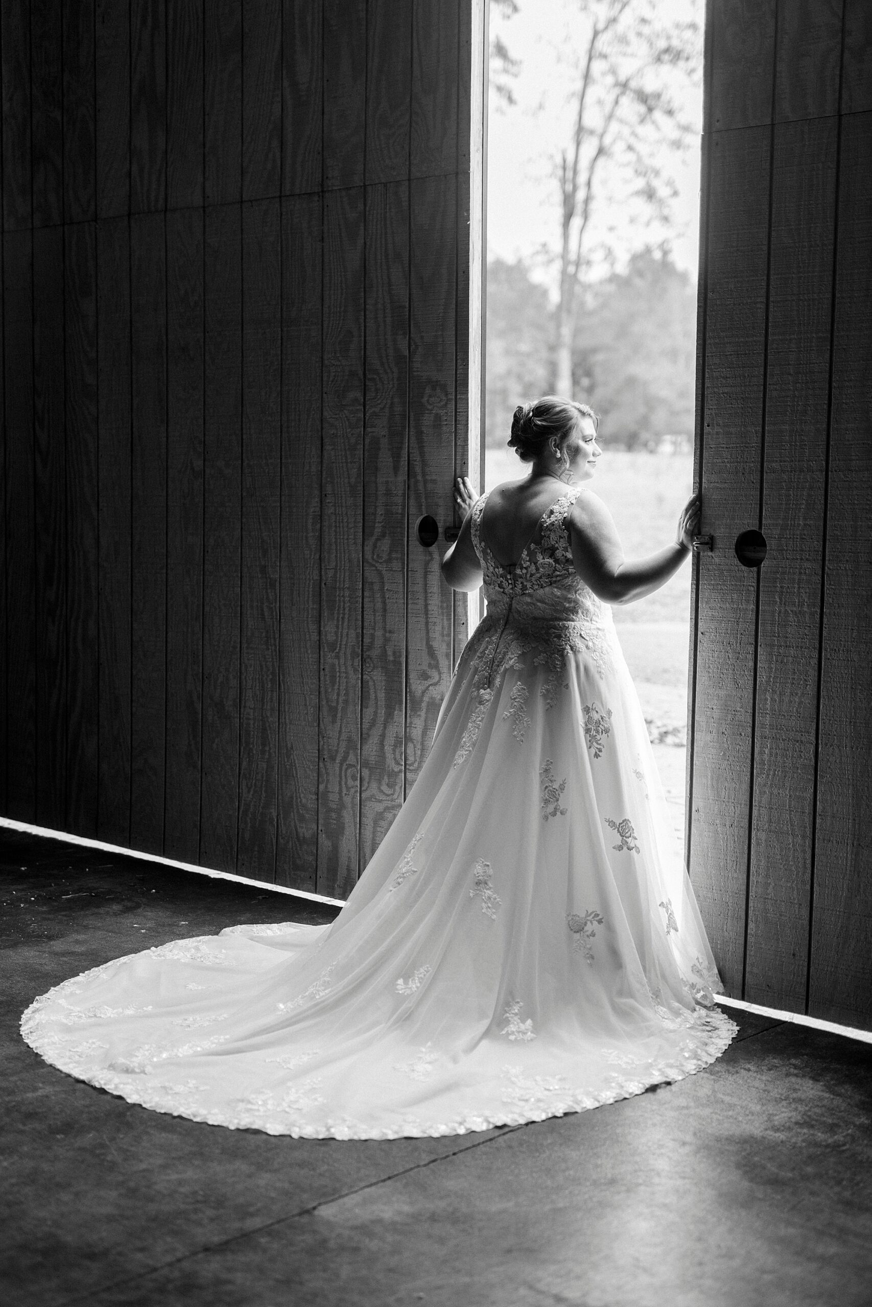 bride looks out doors of barn at the Farm at Brusharbor