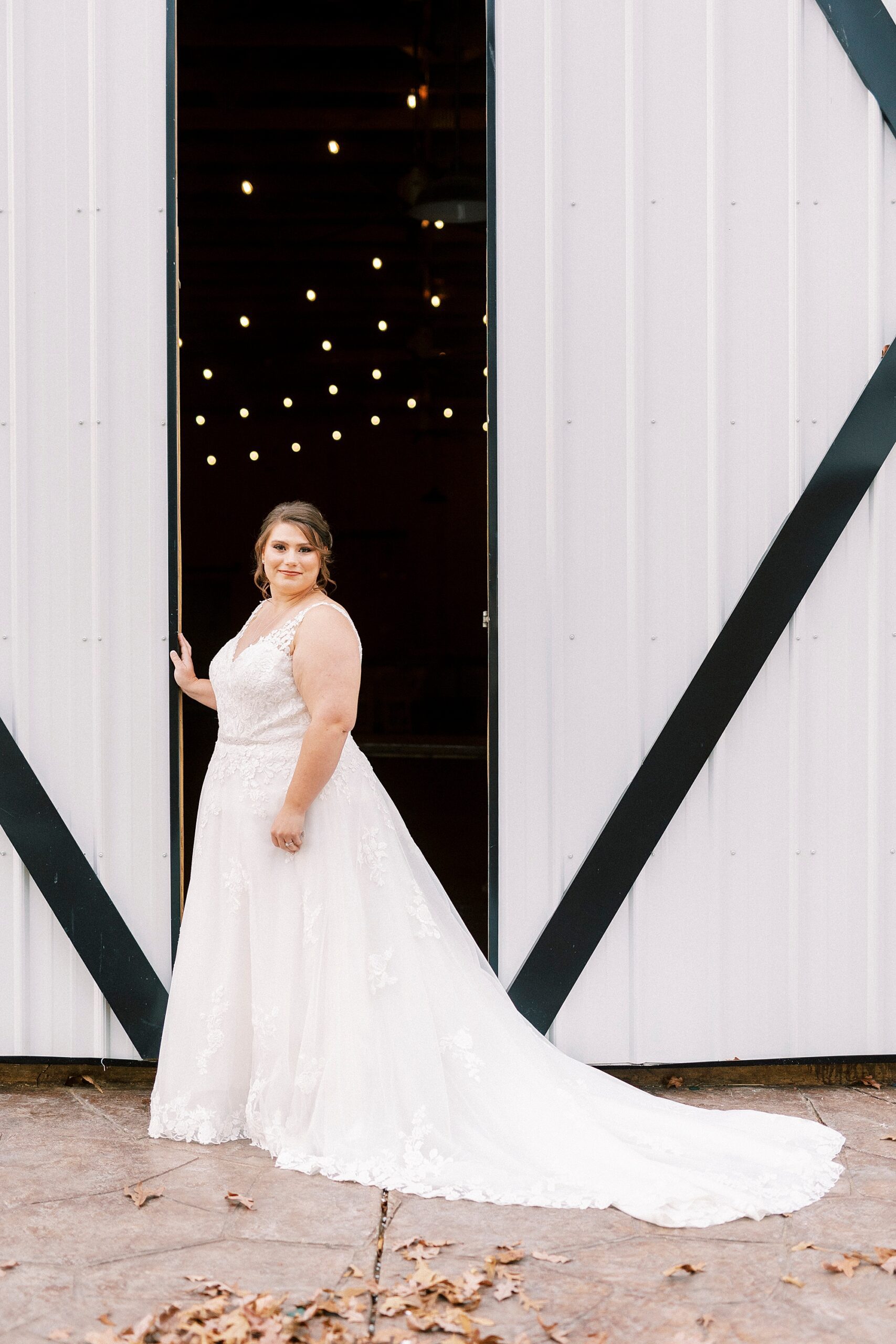 bride stands between barn doors at the Farm at Brusharbor