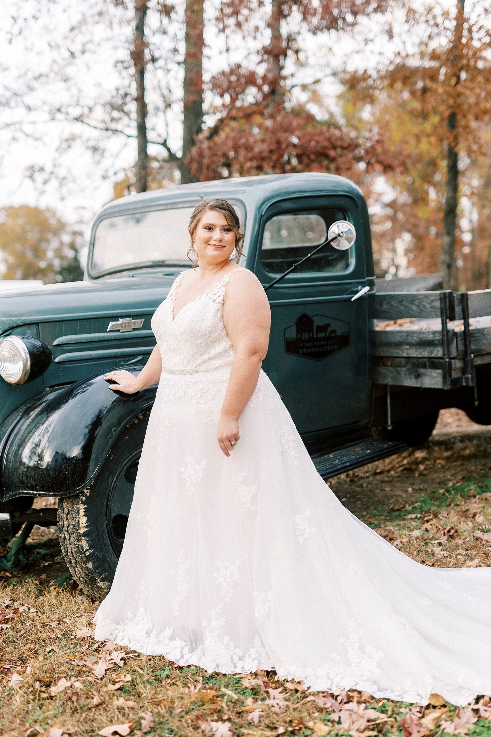 bride poses against vintage blue truck at the Farm at Brusharbor