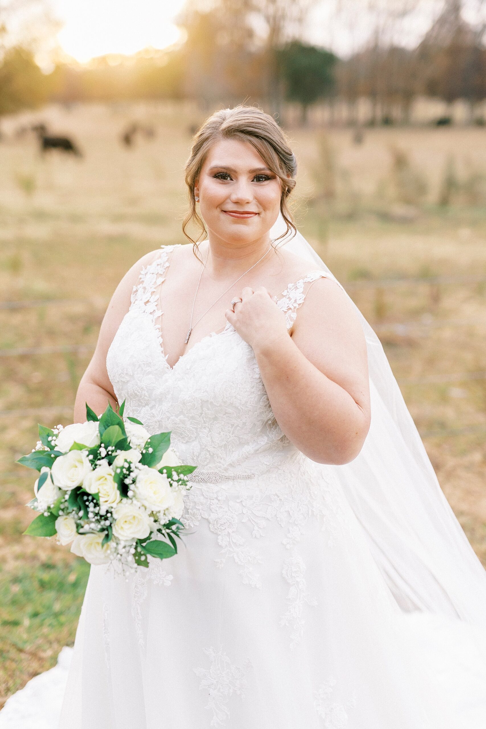 bride smiles holding bouquet of white flowers in field with vows at the Farm at Brusharbor