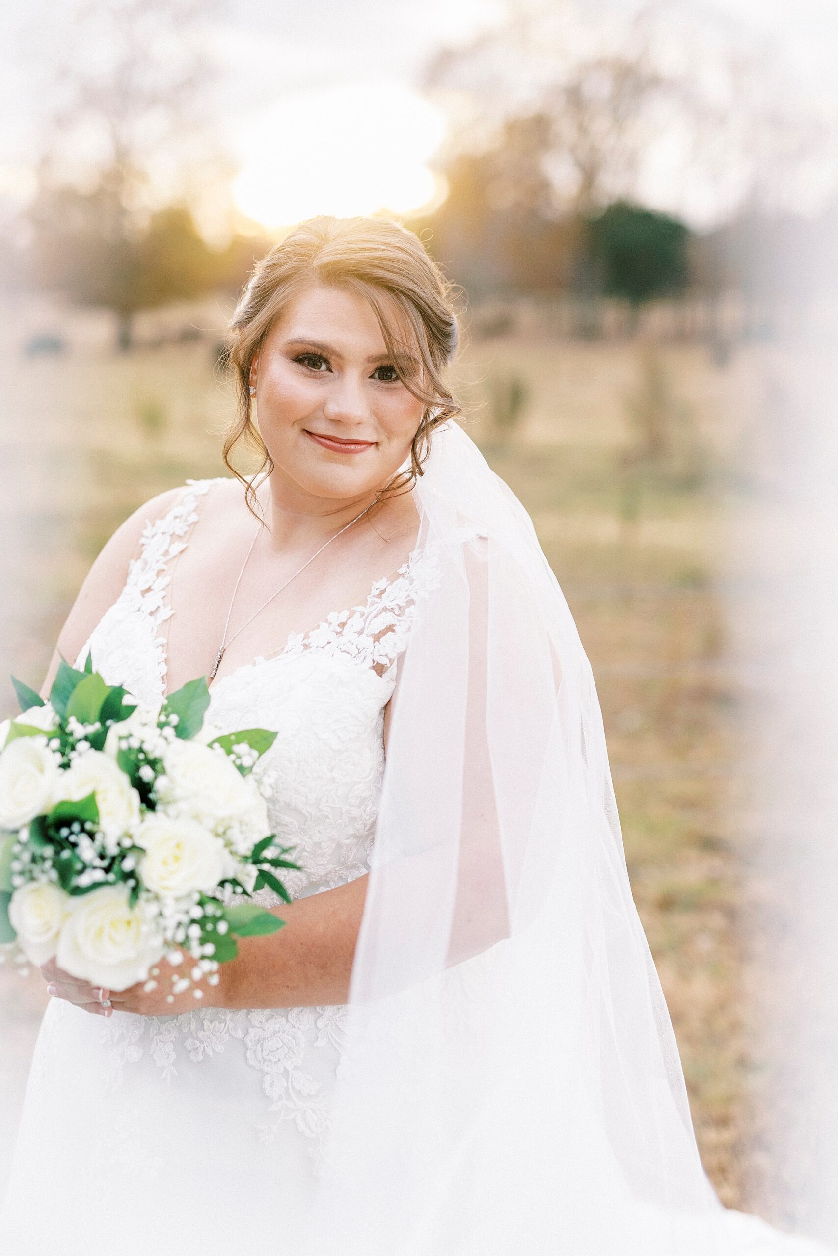 bride smiles leaning over her shoulder with veil around her during fall the Farm at Brusharbor bridal portraits 