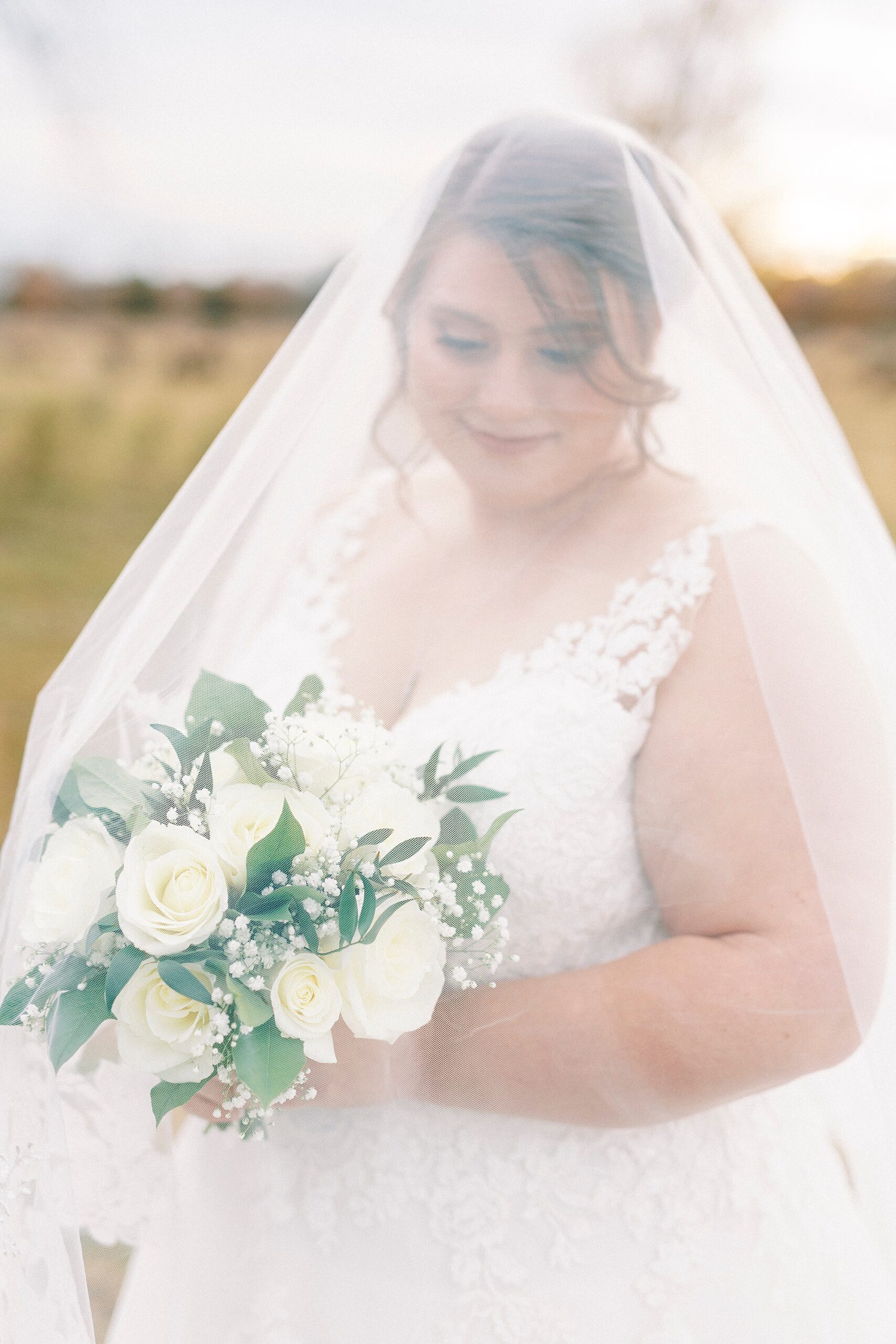 bride smiles down at bouquet during fall bridal portraits at the Farm at Brusharbor