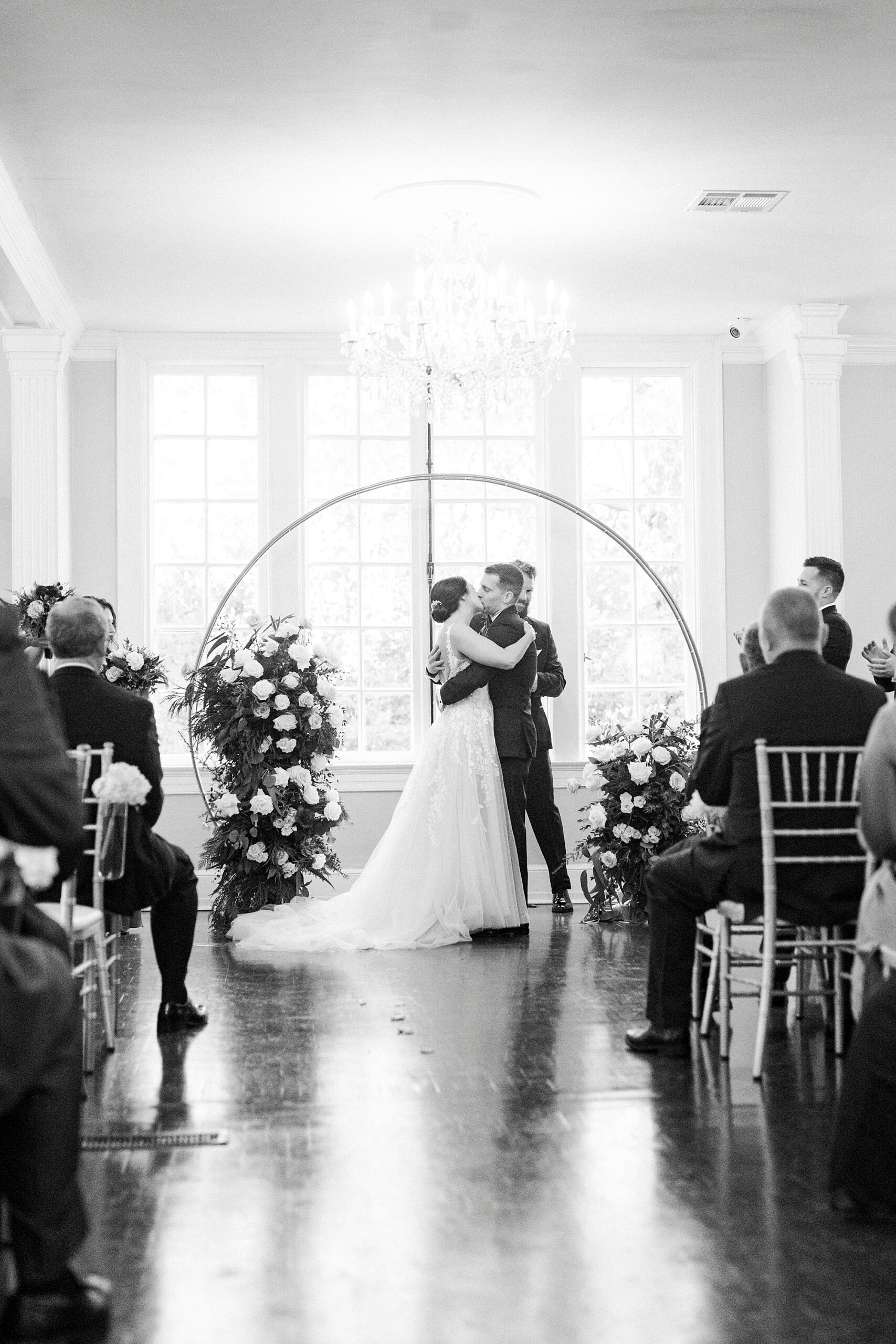 bride and groom kiss under gold arbor during winter wedding ceremony at Separk Mansion